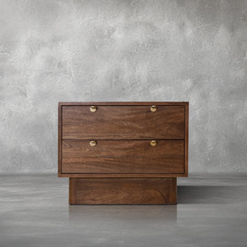 Harper Nightstand in walnut mango wood with two clean drawers and gold half-moon pulls, beside a bed