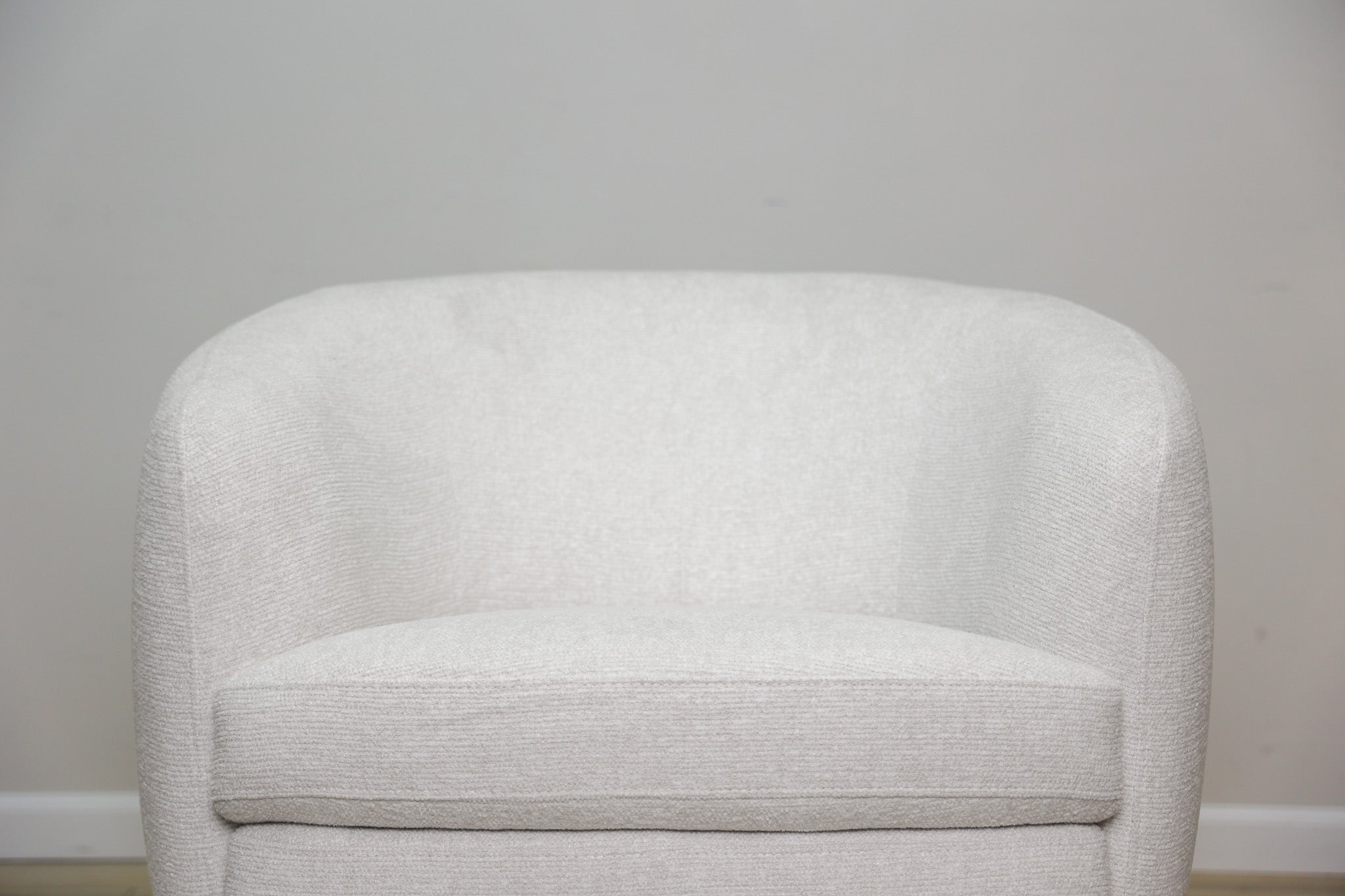 London Swivel Chair in white performance fabric with a curved barrel body on a dark wood swivel base, living room