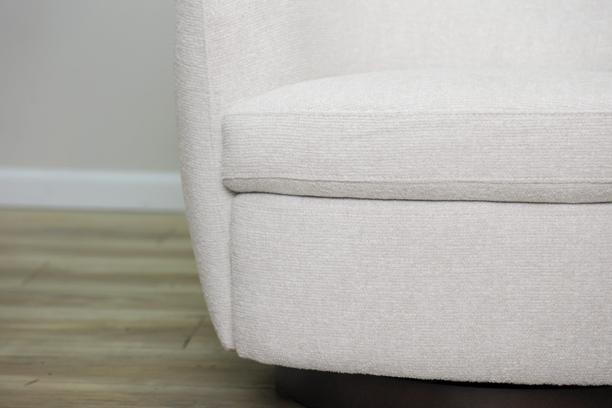 London Swivel Chair in white performance fabric with a curved barrel body on a dark wood swivel base, living room