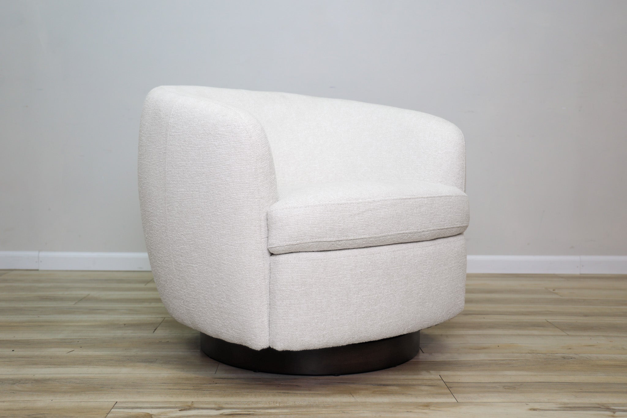 London Swivel Chair in white performance fabric with a curved barrel body on a dark wood swivel base, living room