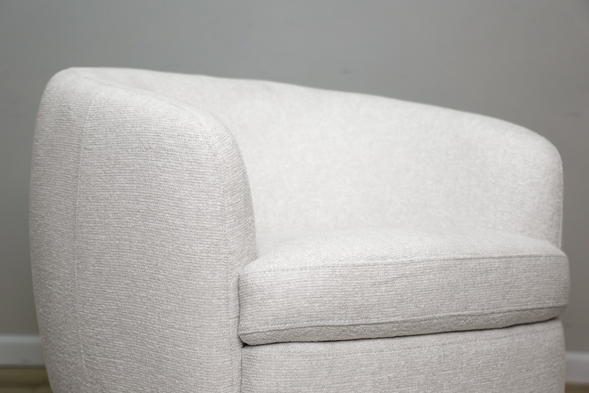 London Swivel Chair in white performance fabric with a curved barrel body on a dark wood swivel base, living room