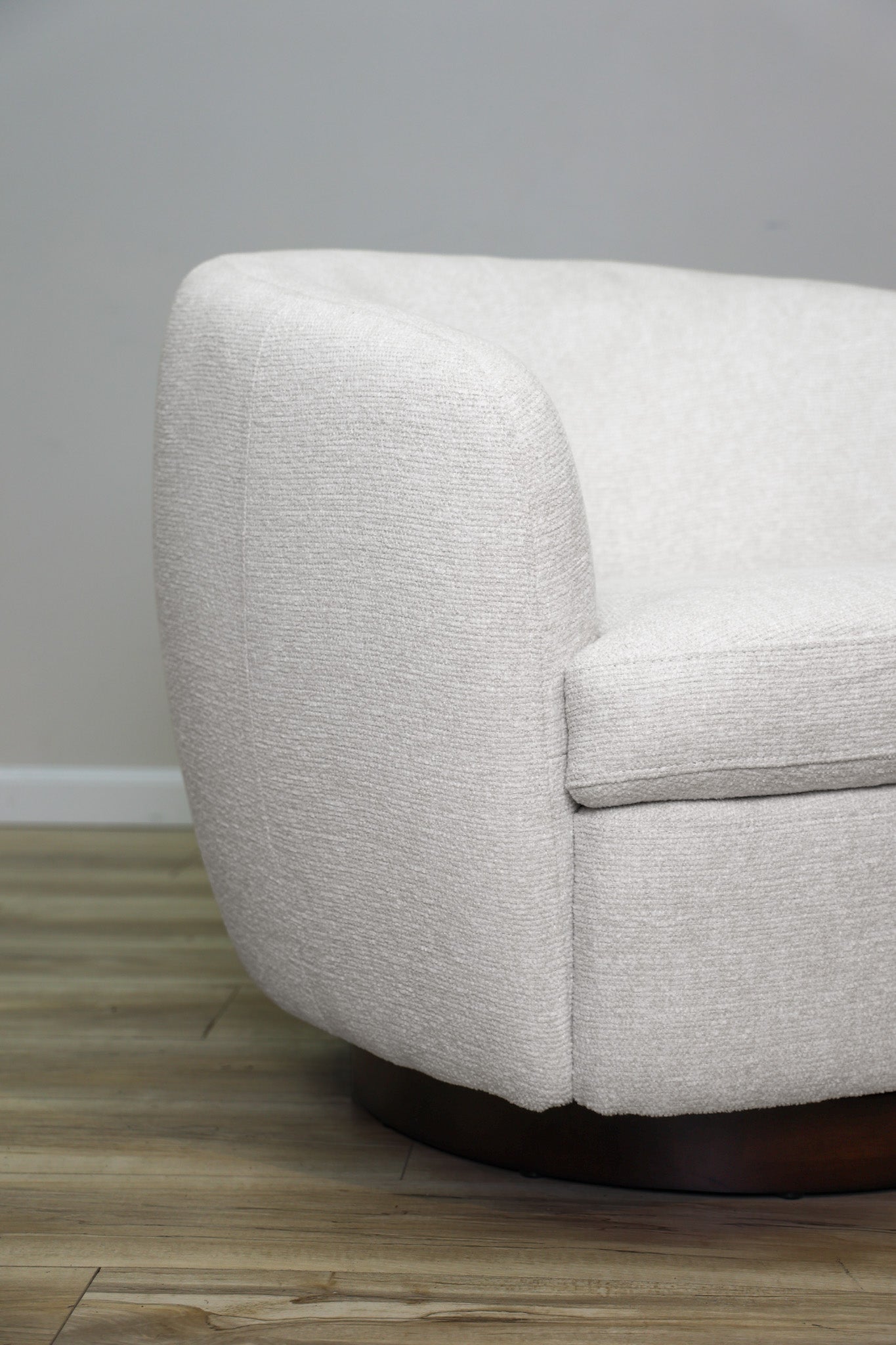 London Swivel Chair in white performance fabric with a curved barrel body on a dark wood swivel base, living room