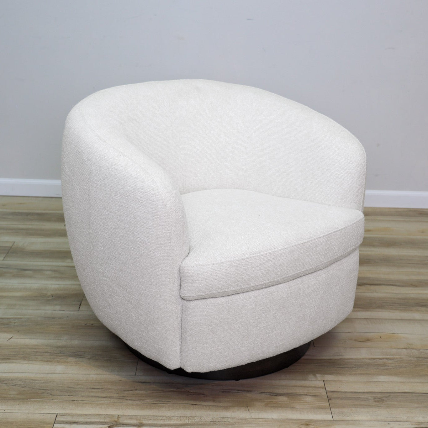 London Swivel Chair in white performance fabric with a curved barrel body on a dark wood swivel base, living room