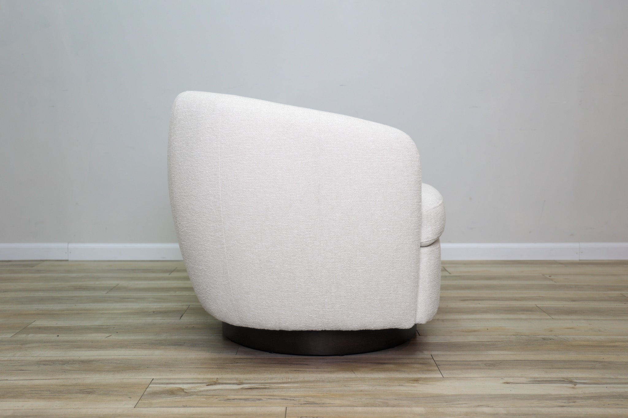 London Swivel Chair in white performance fabric with a curved barrel body on a dark wood swivel base, living room