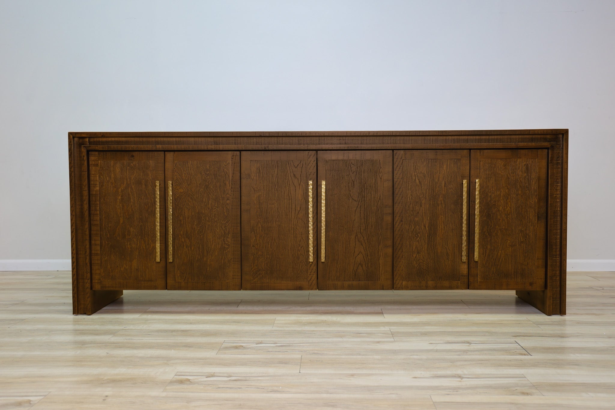Manny 97-inch credenza in solid Mexican pine with six doors and hammered gold bar handles, living room