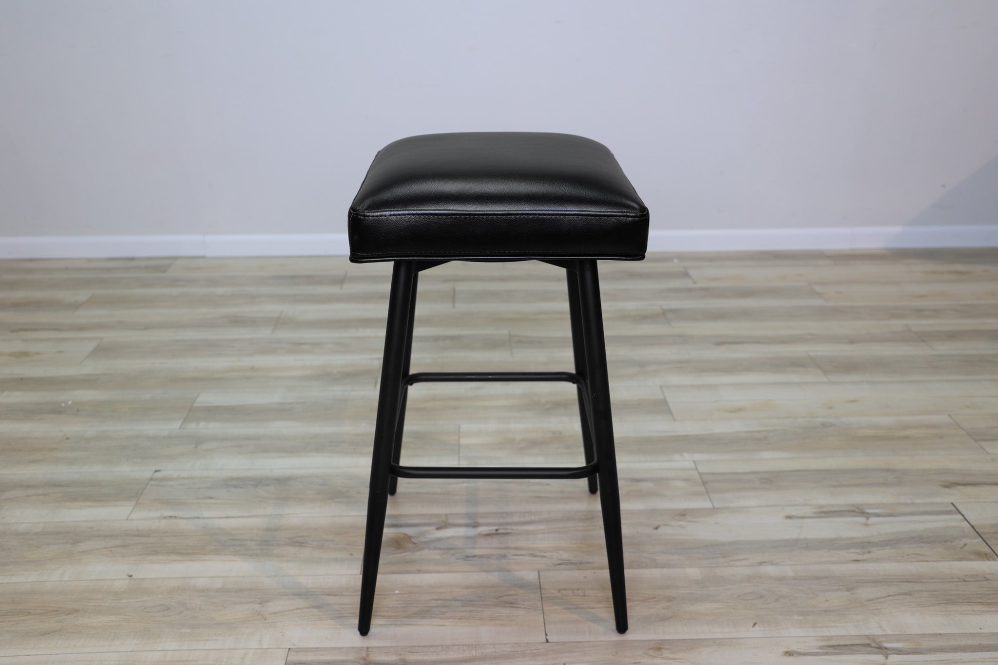 Versa backless adjustable stool in black faux leather with a black metal swivel base and footrest, kitchen bar