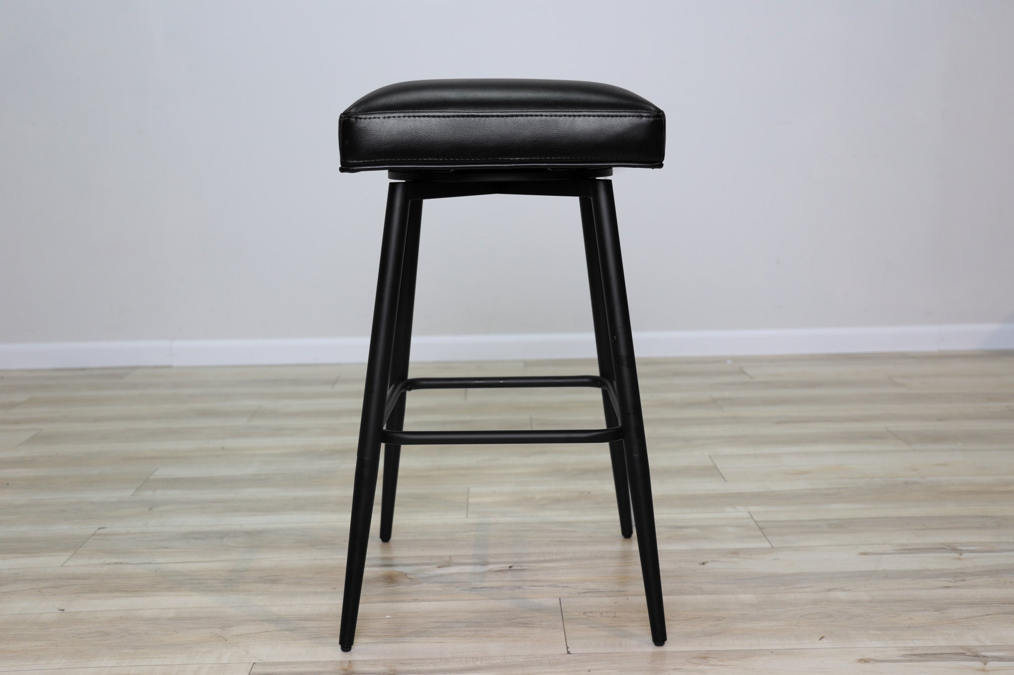 Versa backless adjustable stool in black faux leather with a black metal swivel base and footrest, kitchen bar