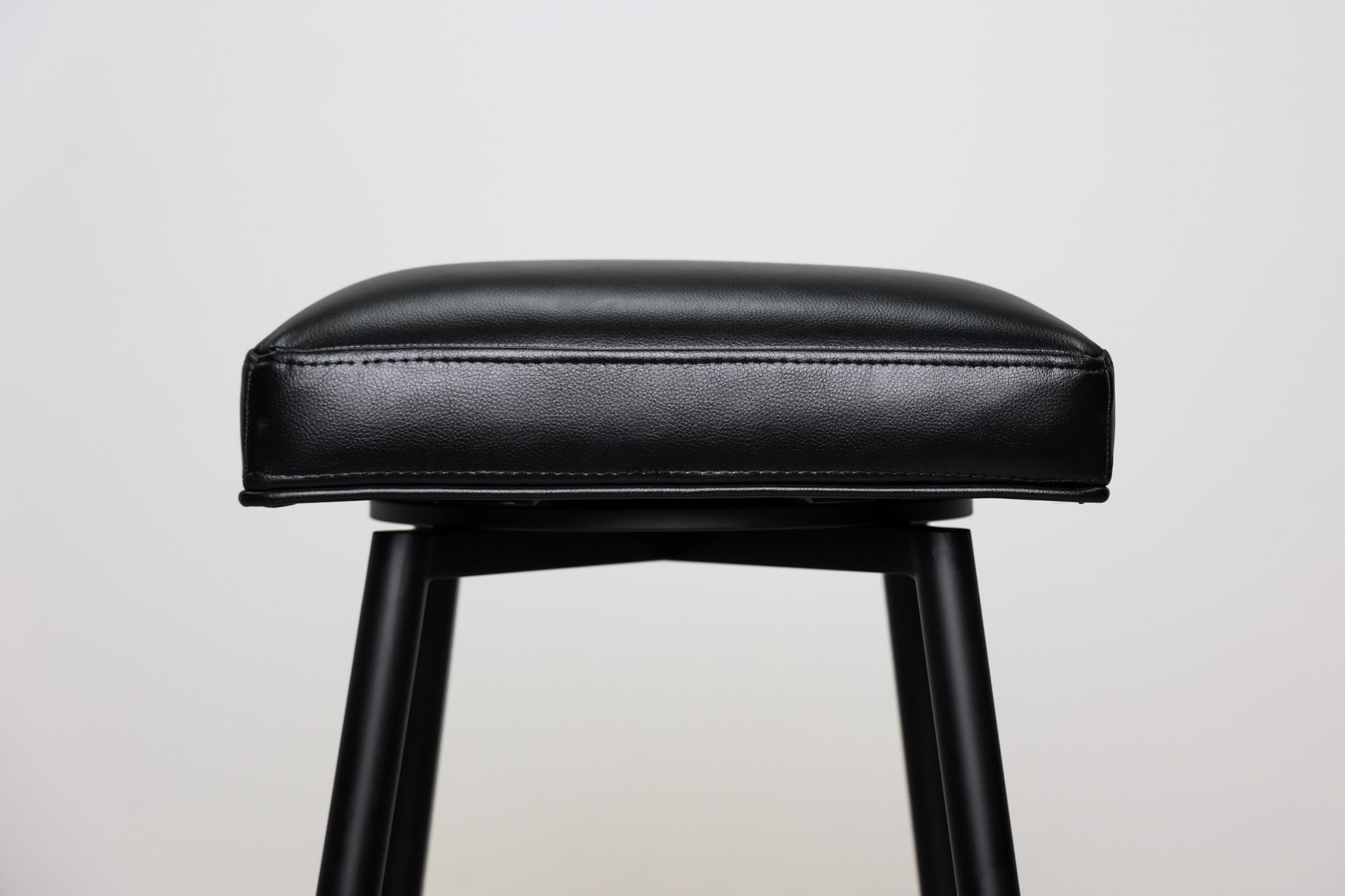 Versa backless adjustable stool in black faux leather with a black metal swivel base and footrest, kitchen bar