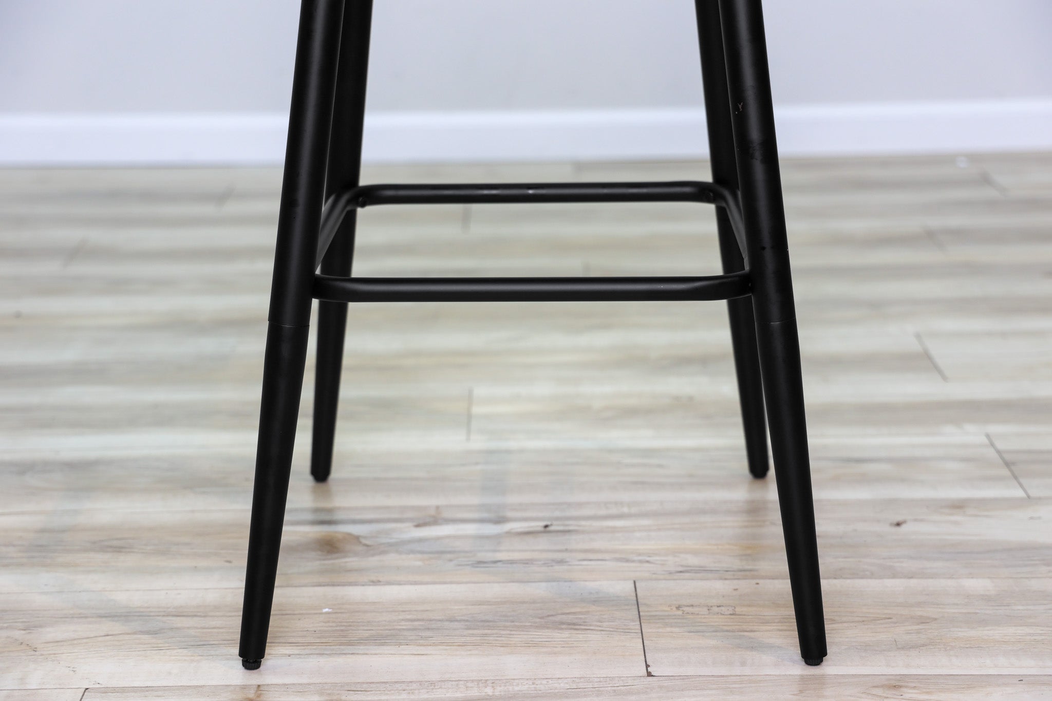 Versa backless adjustable stool in black faux leather with a black metal swivel base and footrest, kitchen bar