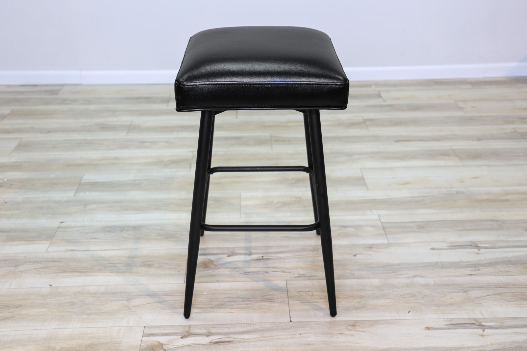 Versa backless adjustable stool in black faux leather with a black metal swivel base and footrest, kitchen bar