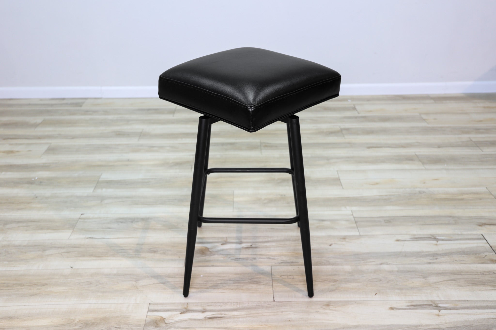 Versa backless adjustable stool in black faux leather with a black metal swivel base and footrest, kitchen bar