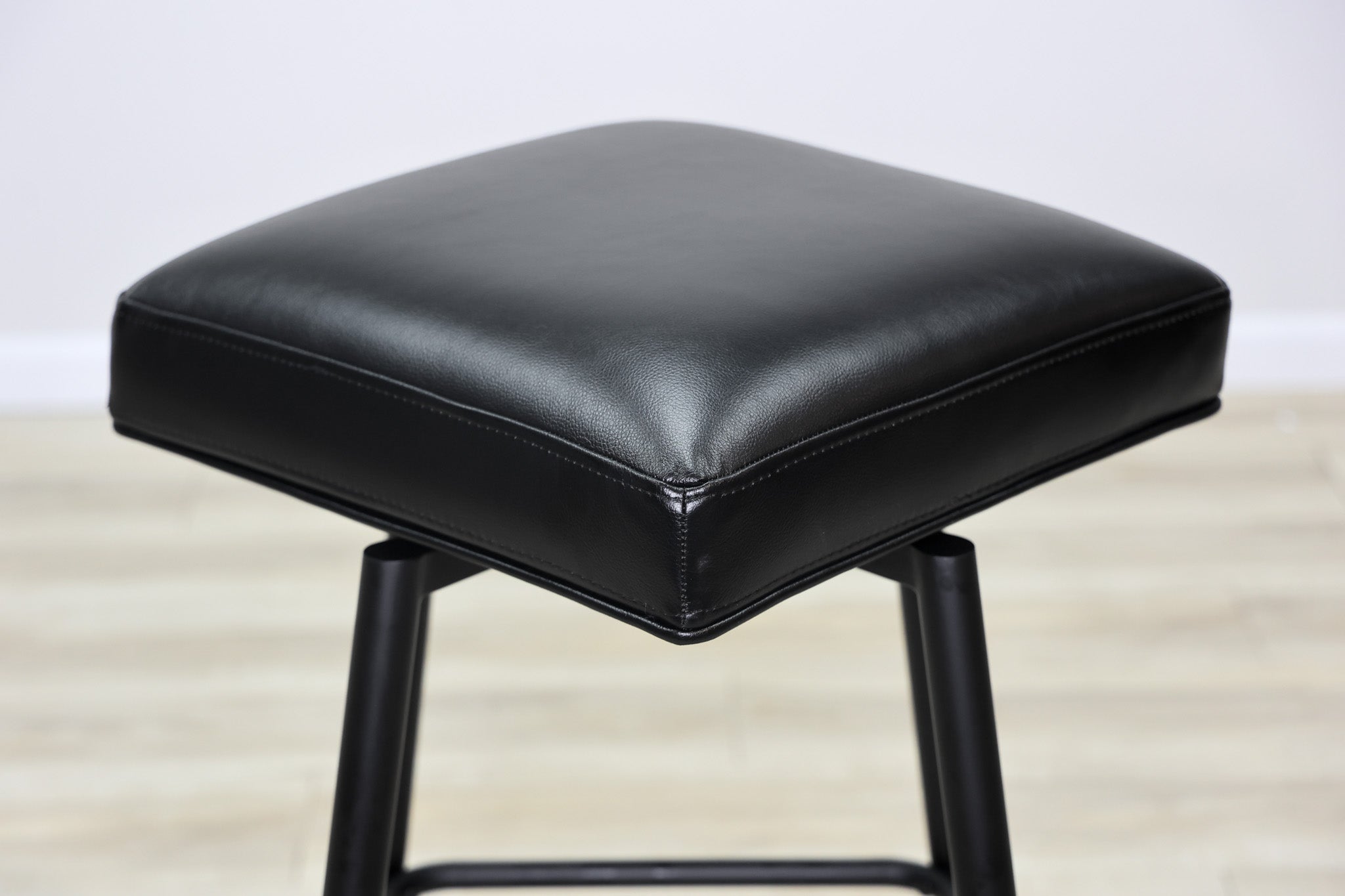 Versa backless adjustable stool in black faux leather with a black metal swivel base and footrest, kitchen bar