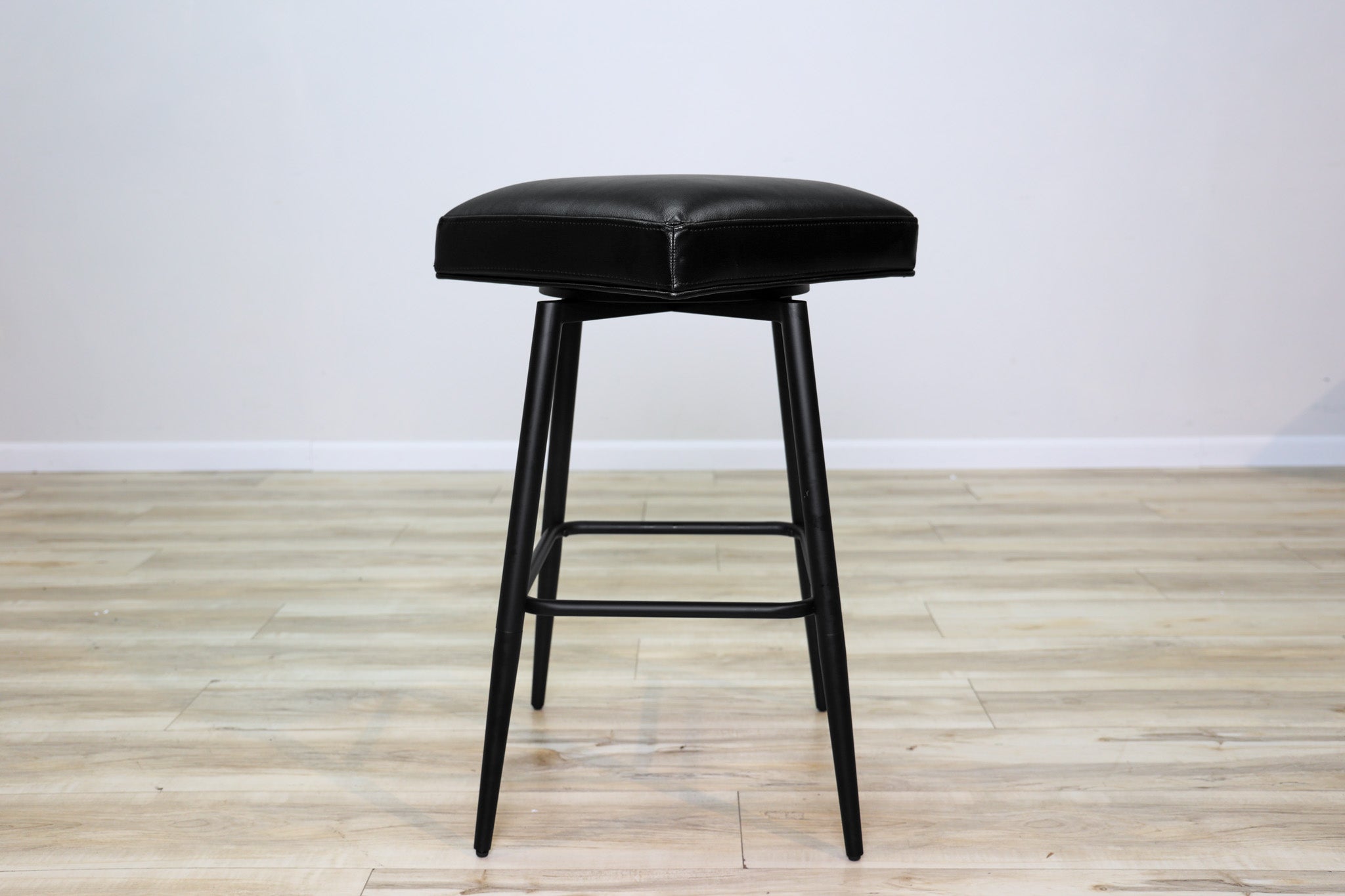 Versa backless adjustable stool in black faux leather with a black metal swivel base and footrest, kitchen bar