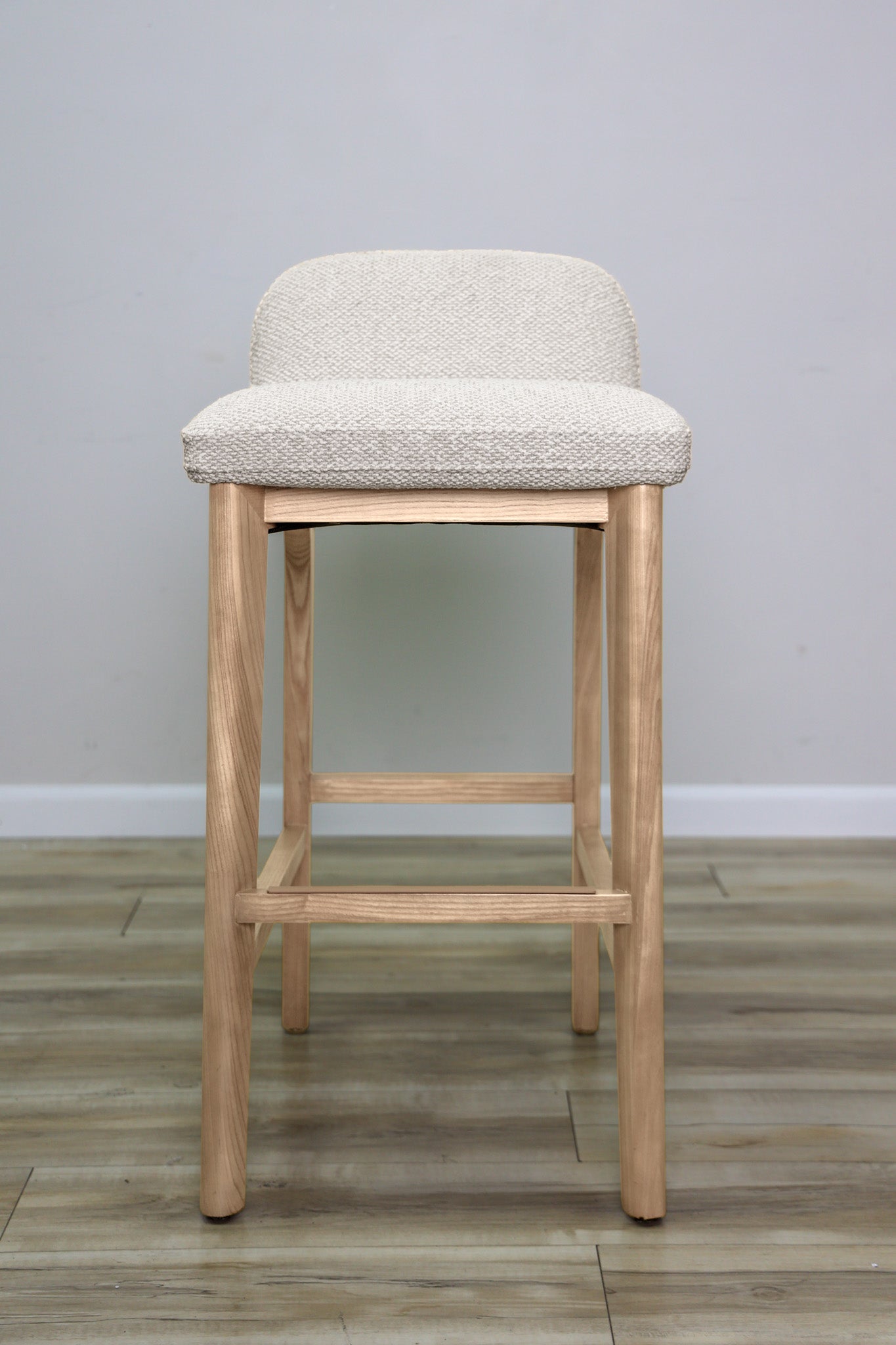 Asher barstool in beige performance fabric with a low back and natural wood legs with stretchers, kitchen bar