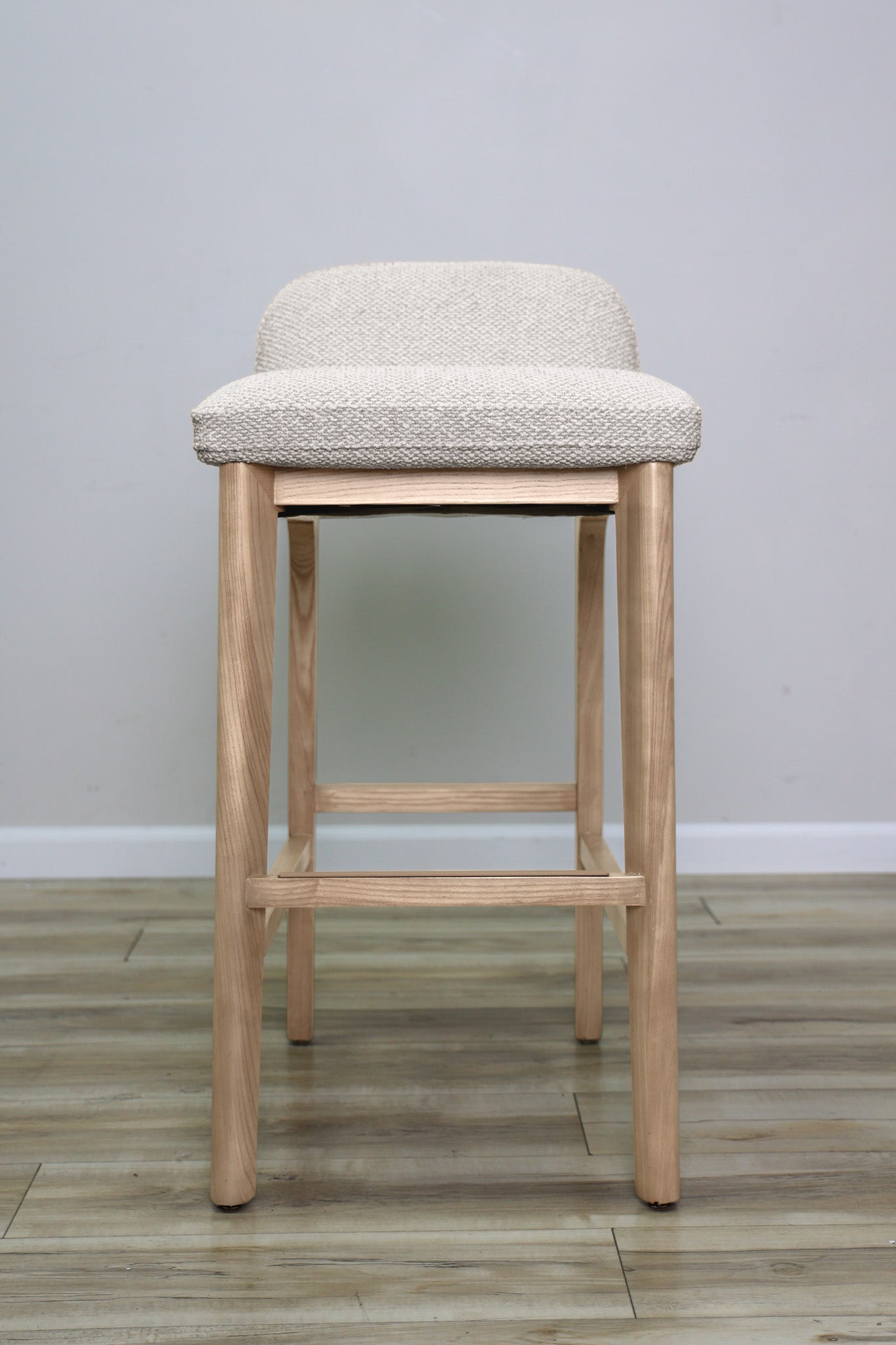 Asher barstool in beige performance fabric with a low back and natural wood legs with stretchers, kitchen bar