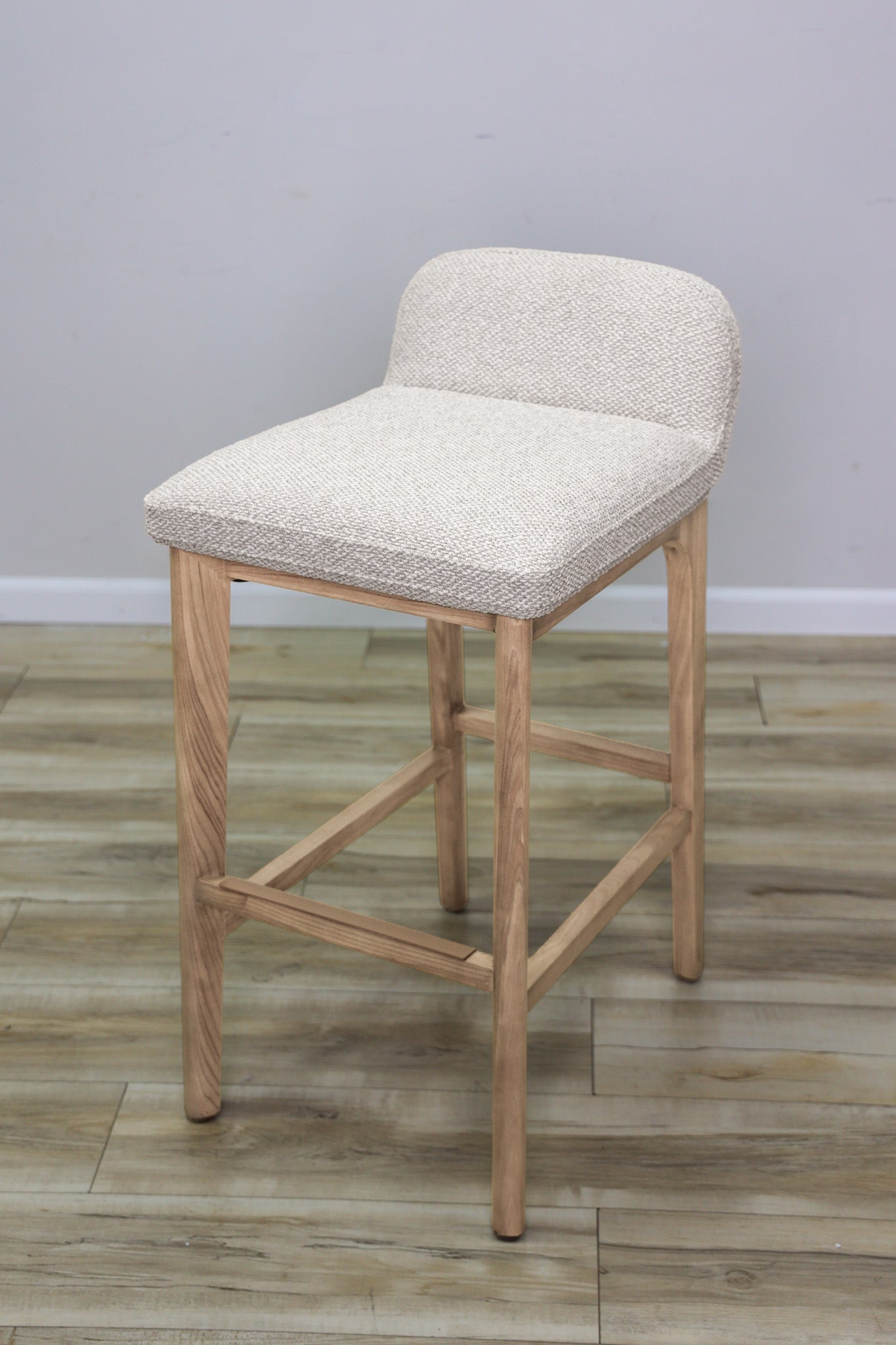 Asher barstool in beige performance fabric with a low back and natural wood legs with stretchers, kitchen bar