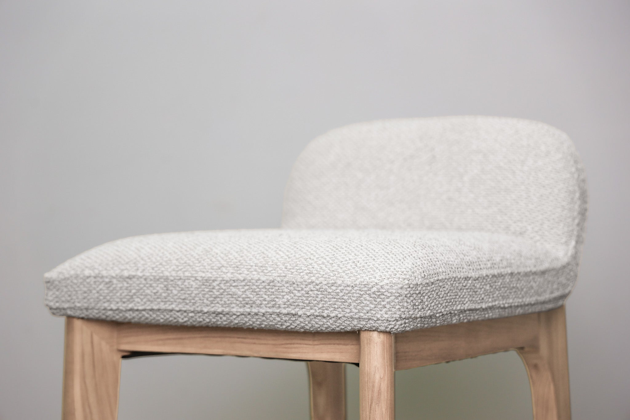 Asher barstool in beige performance fabric with a low back and natural wood legs with stretchers, kitchen bar