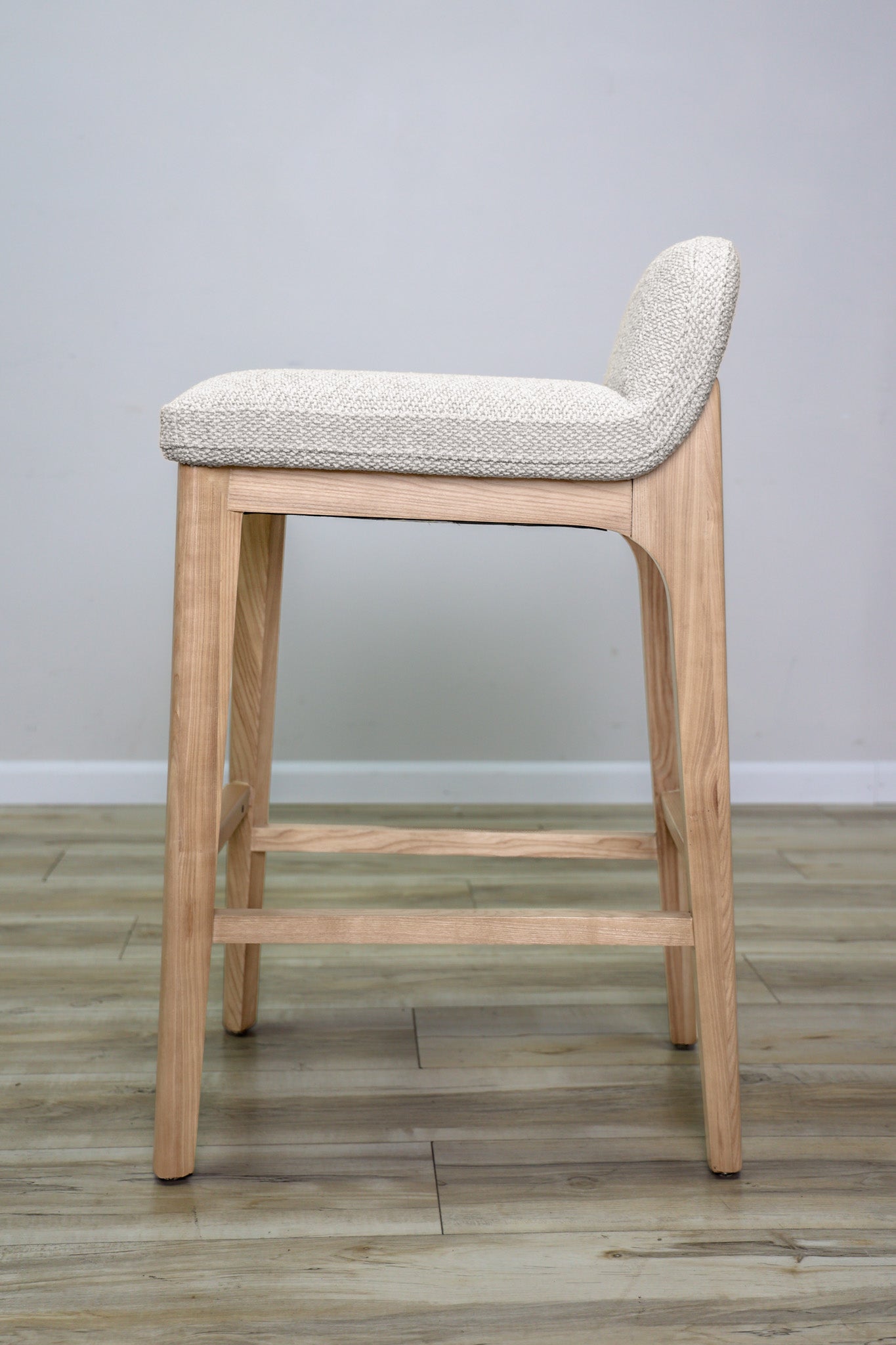 Asher barstool in beige performance fabric with a low back and natural wood legs with stretchers, kitchen bar
