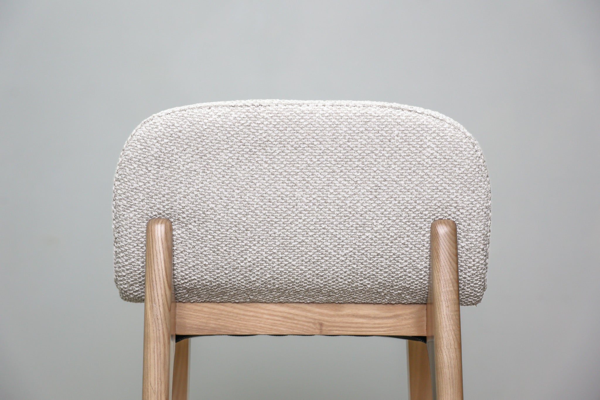 Asher barstool in beige performance fabric with a low back and natural wood legs with stretchers, kitchen bar