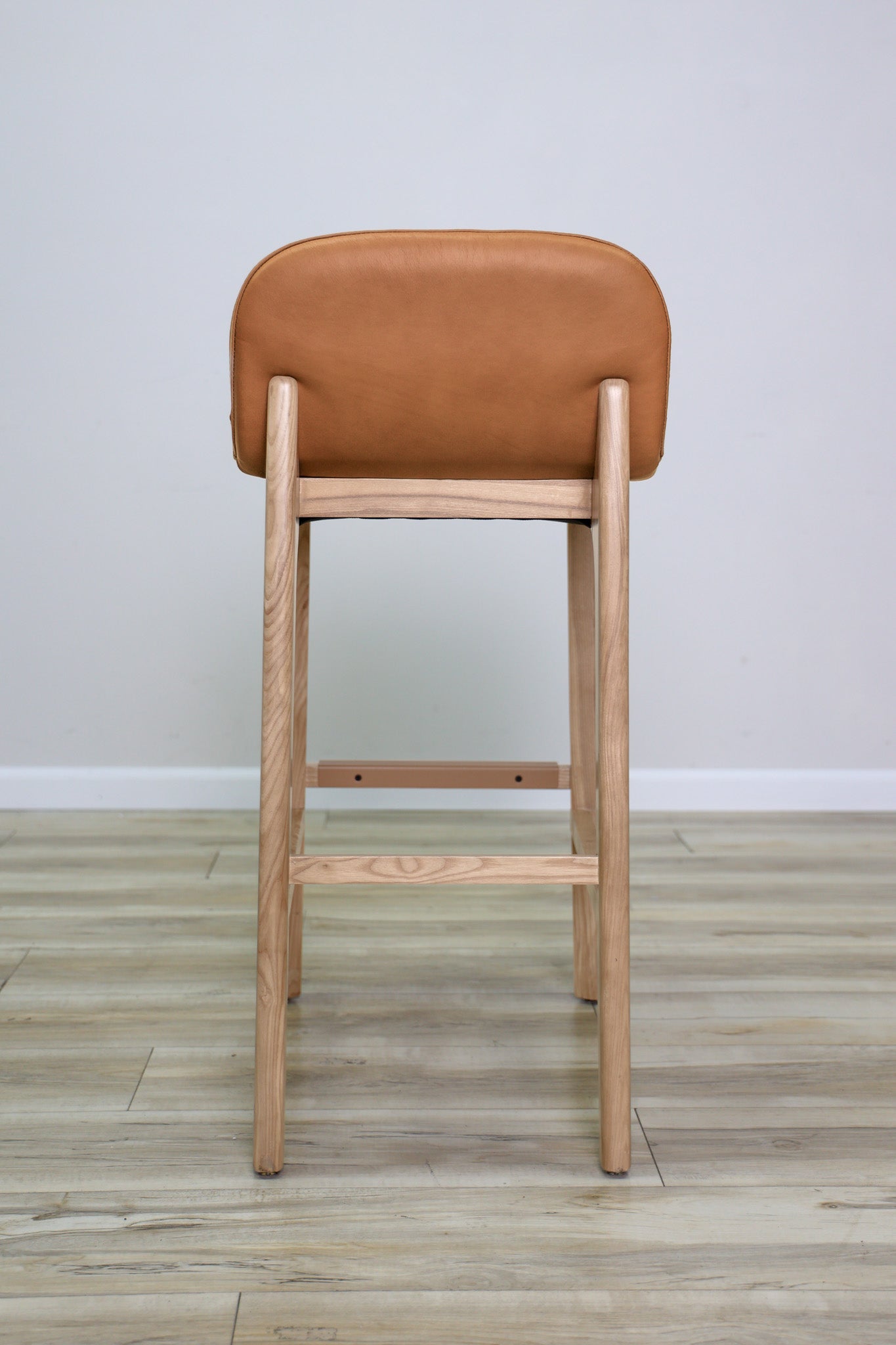 Sable barstool in cognac leather with a low back and natural wood legs with stretchers, kitchen bar