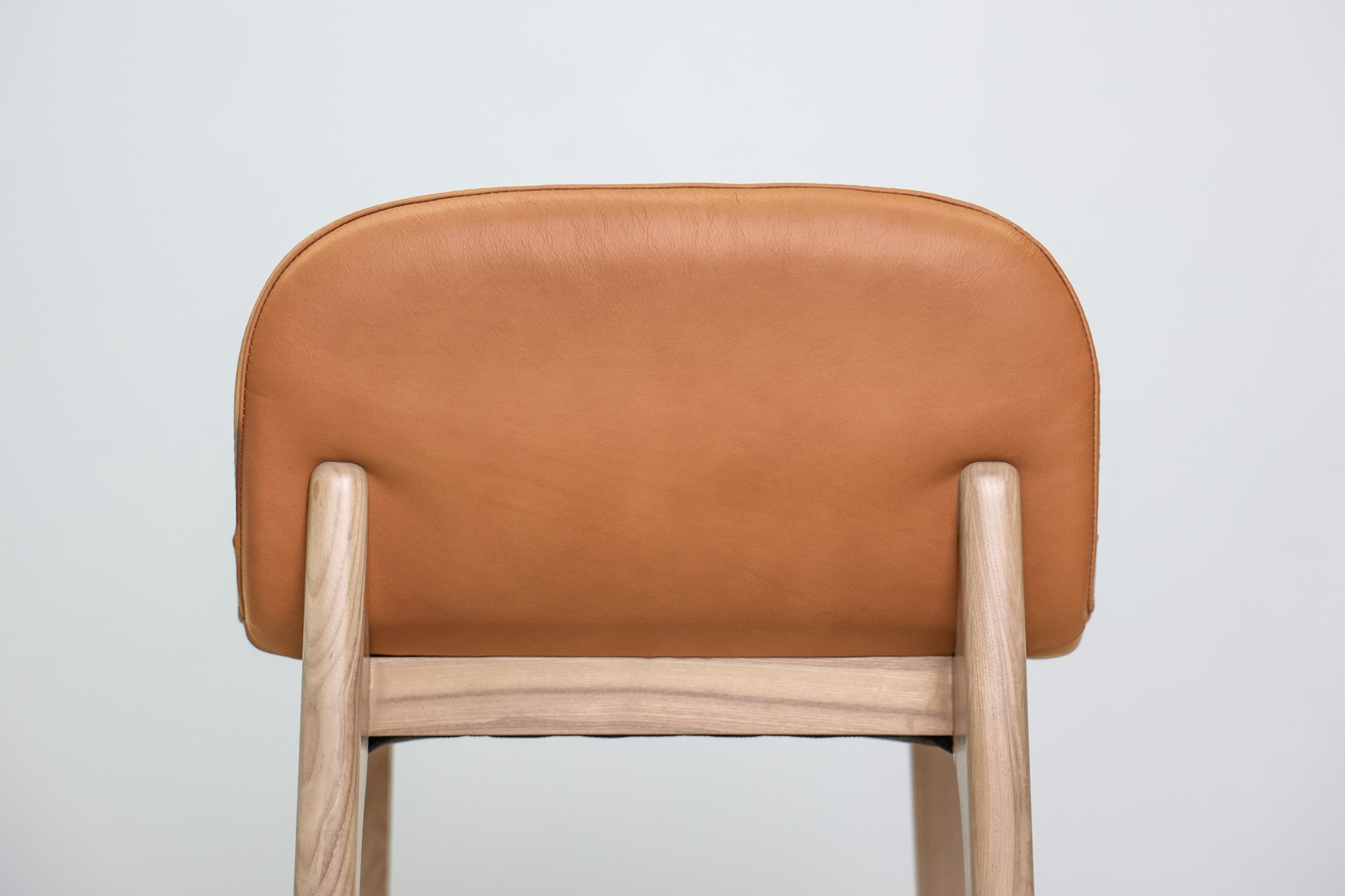Sable barstool in cognac leather with a low back and natural wood legs with stretchers, kitchen bar