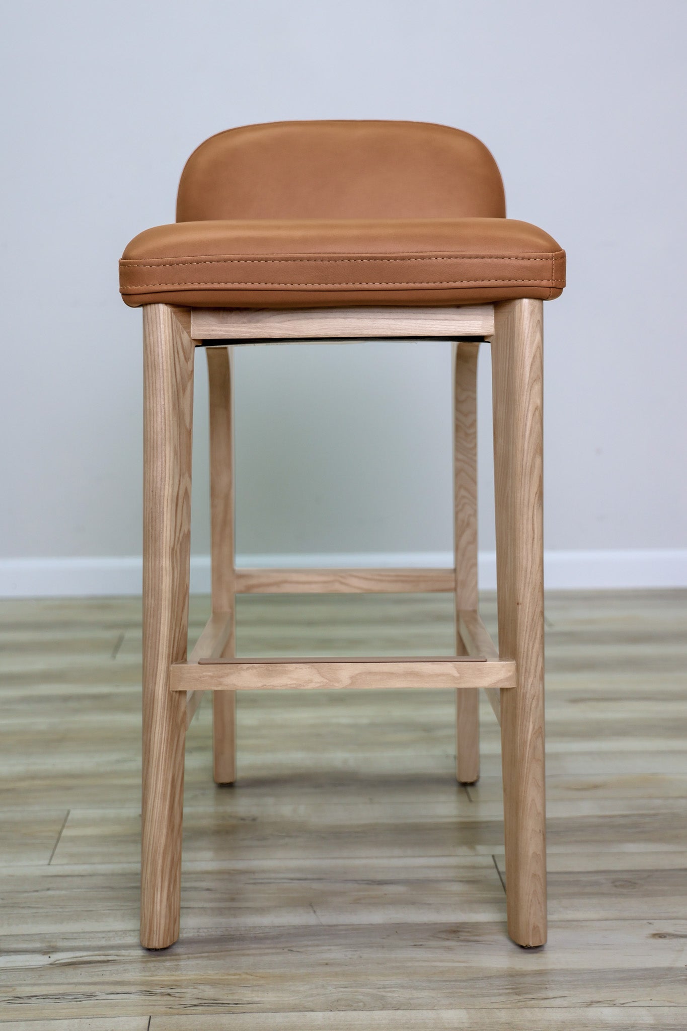 Sable barstool in cognac leather with a low back and natural wood legs with stretchers, kitchen bar