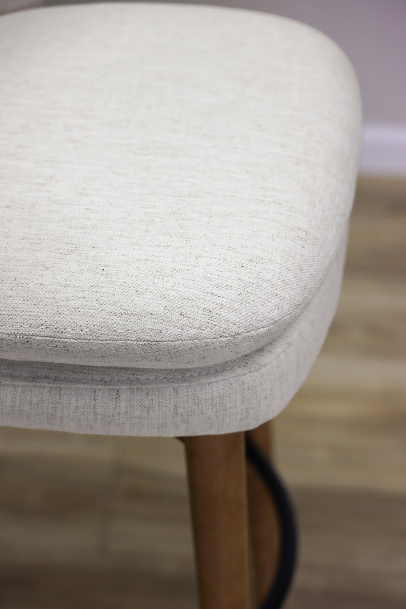 Tiffany swivel barstool in ivory Crypton fabric with natural wood legs and a black ring footrest, kitchen bar