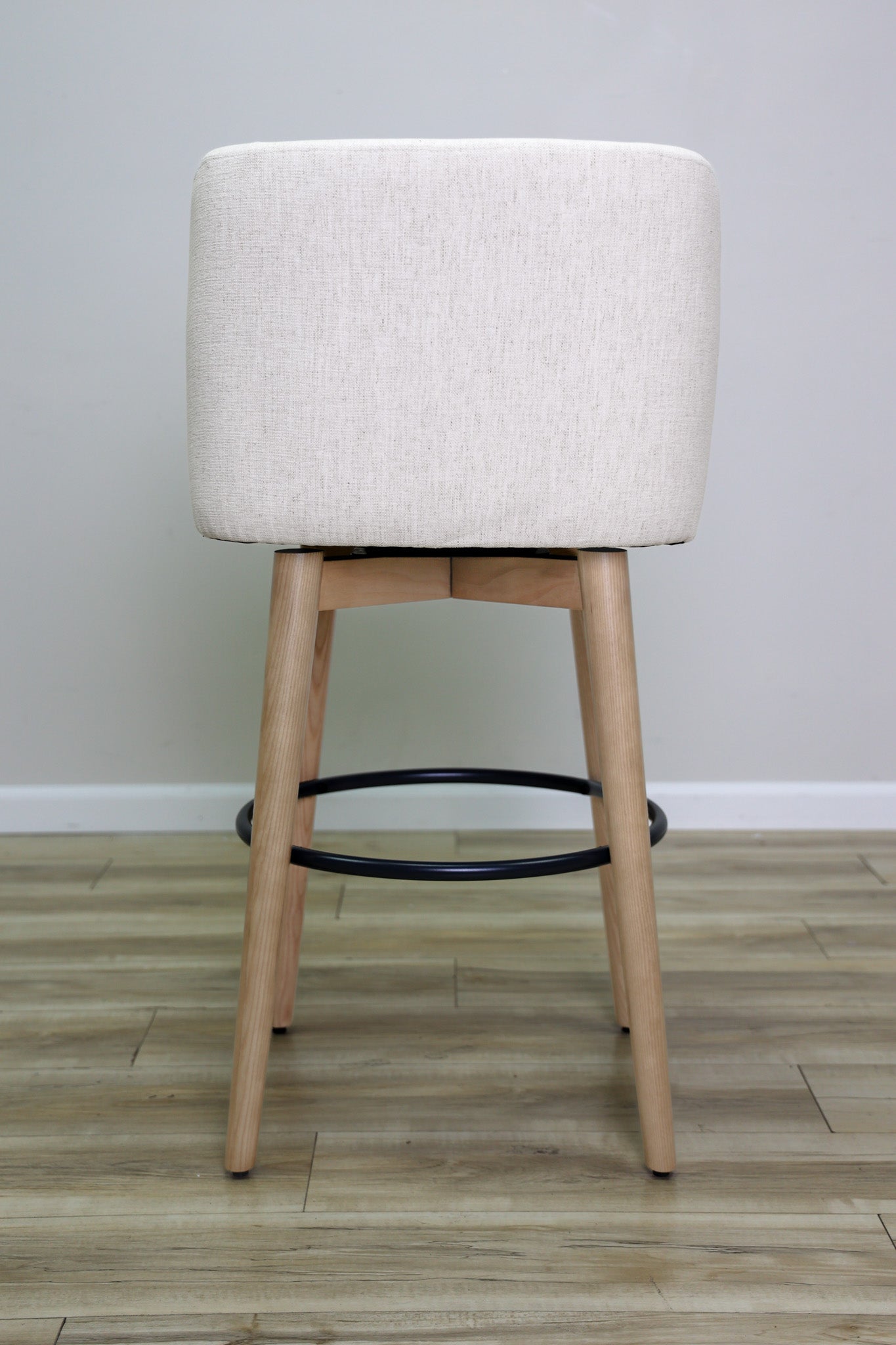 Tiffany swivel barstool in ivory Crypton fabric with natural wood legs and a black ring footrest, kitchen bar