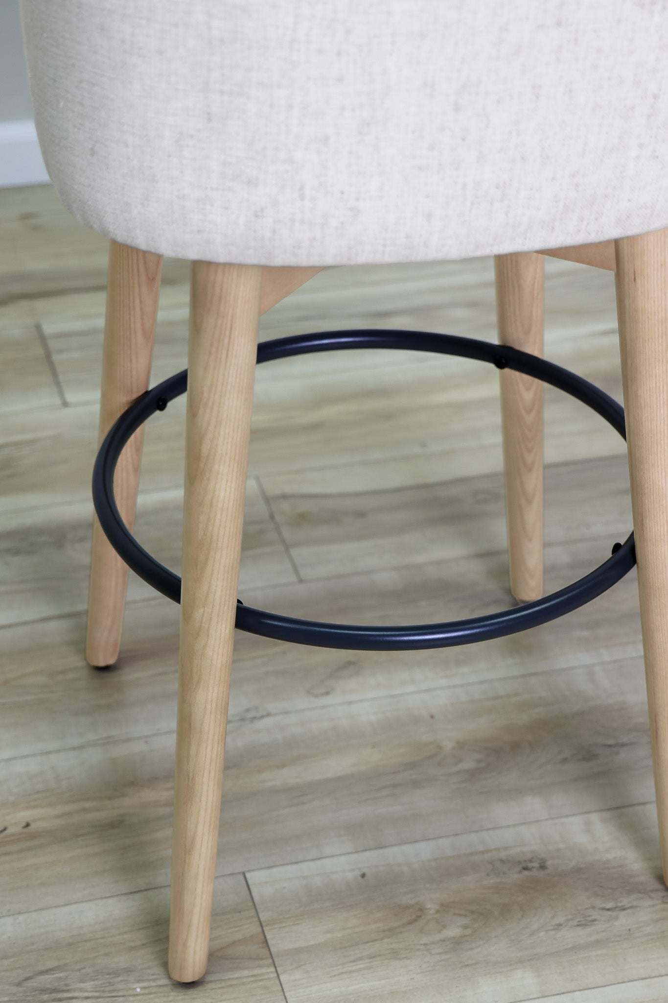 Tiffany swivel barstool in ivory Crypton fabric with natural wood legs and a black ring footrest, kitchen bar