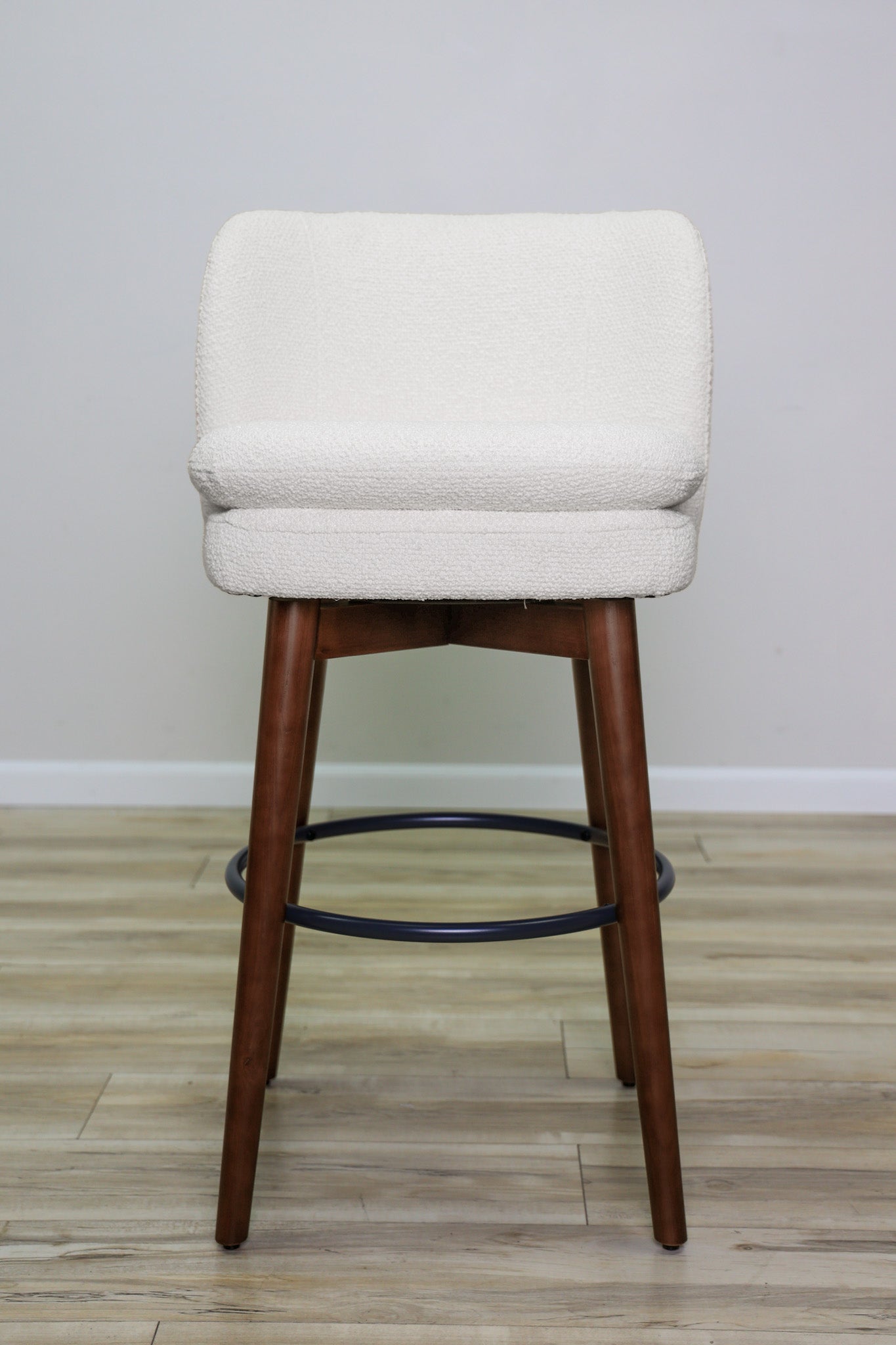 Avalon swivel barstool in cream bouclé performance fabric with walnut wood legs and a black ring footrest, kitchen bar