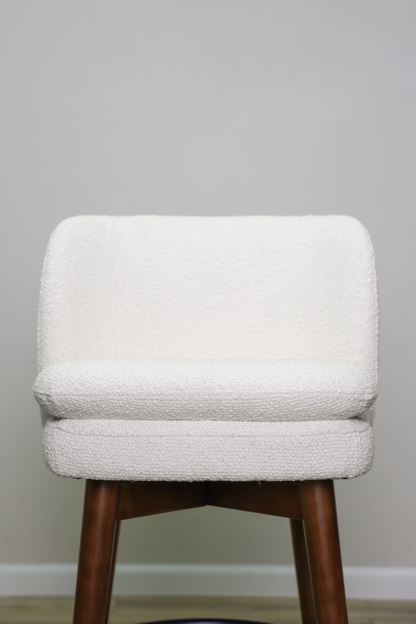 Avalon swivel barstool in cream bouclé performance fabric with walnut wood legs and a black ring footrest, kitchen bar