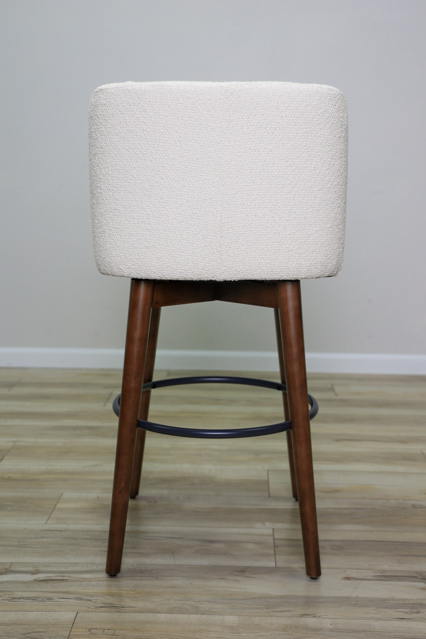 Avalon swivel barstool in cream bouclé performance fabric with walnut wood legs and a black ring footrest, kitchen bar