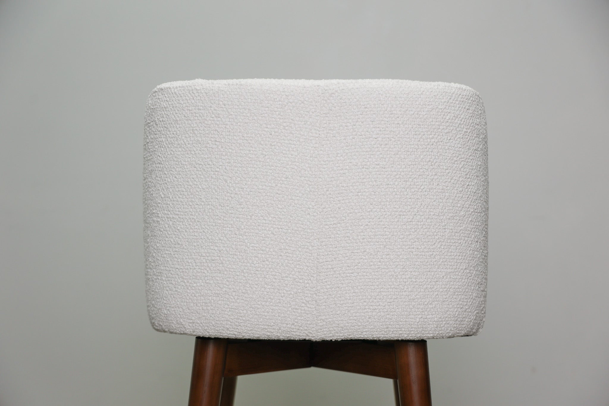Avalon swivel barstool in cream bouclé performance fabric with walnut wood legs and a black ring footrest, kitchen bar