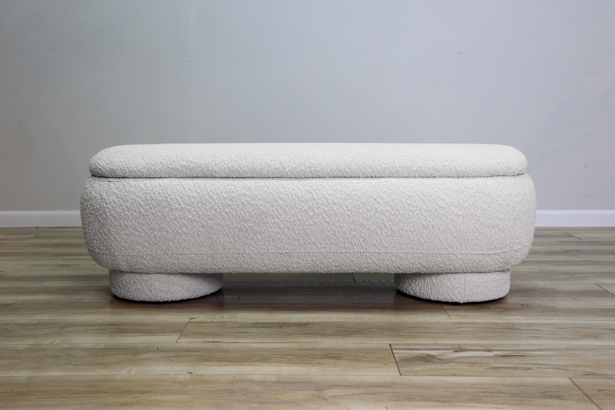 Casper storage bench in creamy white bouclé with a lift-top lid and rounded drum feet, living room