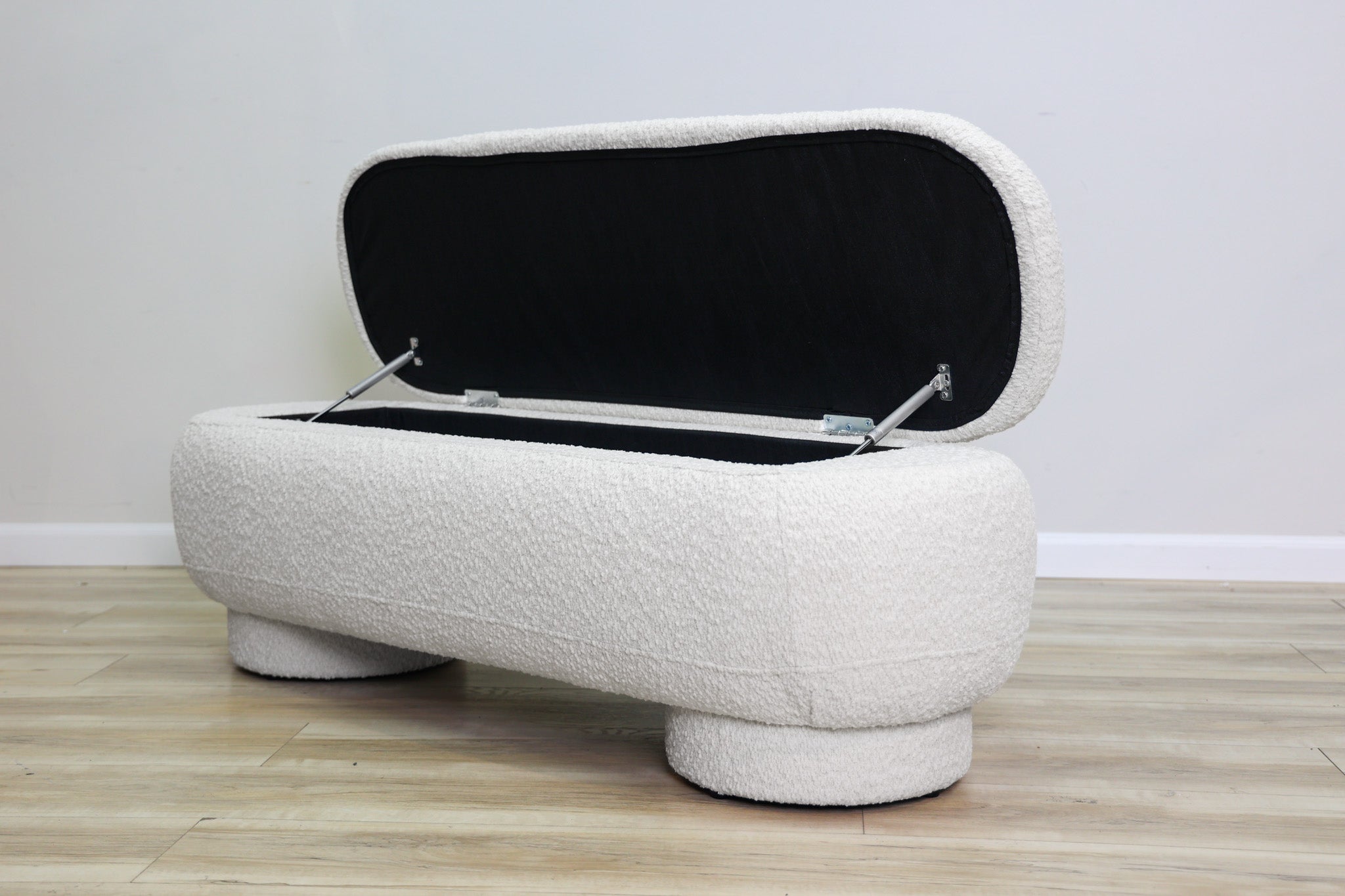 Casper storage bench in creamy white bouclé with a lift-top lid and rounded drum feet, living room