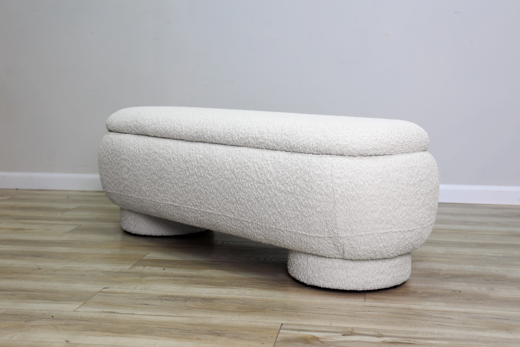 Casper storage bench in creamy white bouclé with a lift-top lid and rounded drum feet, living room