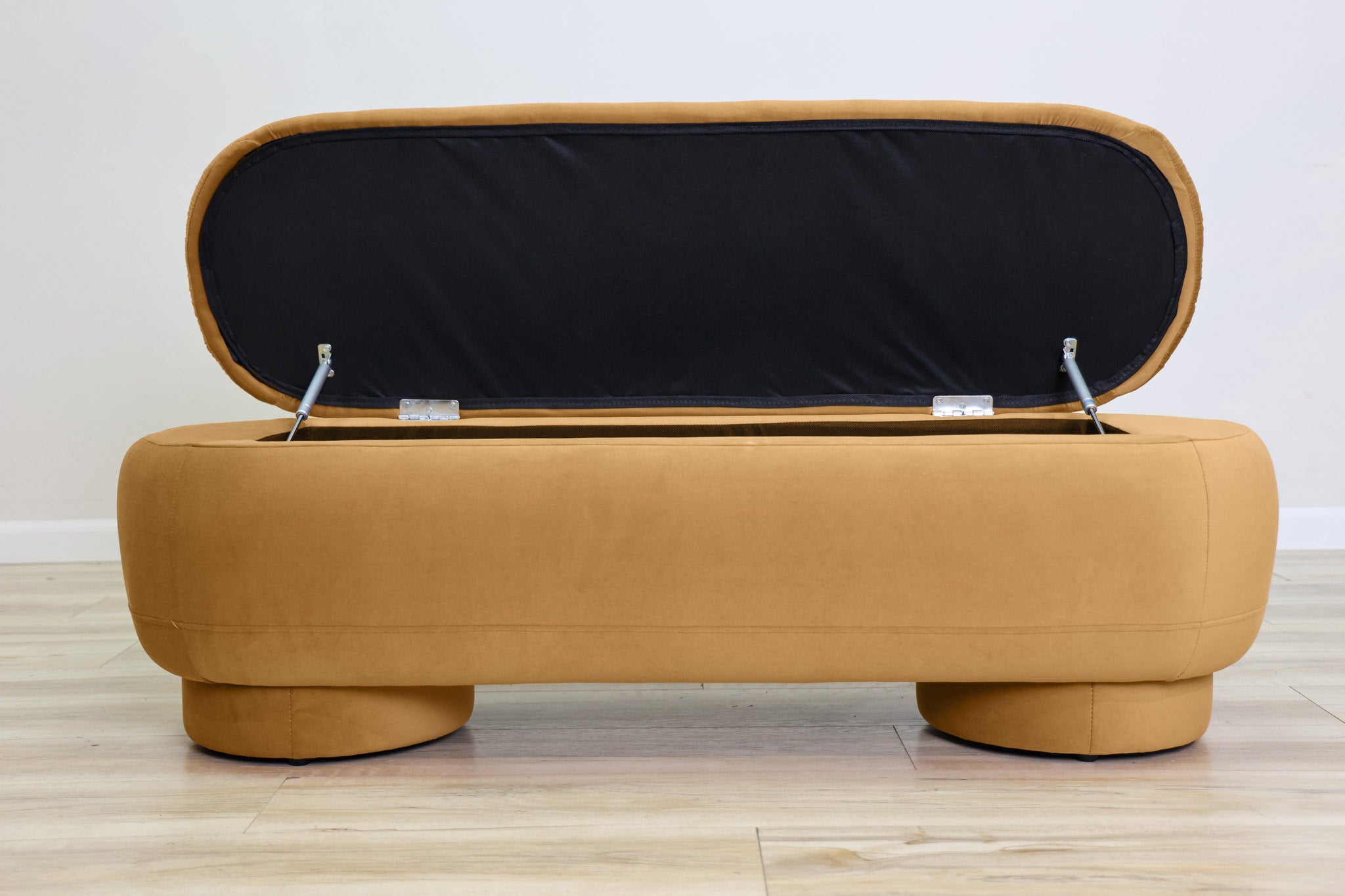 Dorian storage bench in golden velvet with a lift-top lid open to hidden storage and rounded drum feet, living room