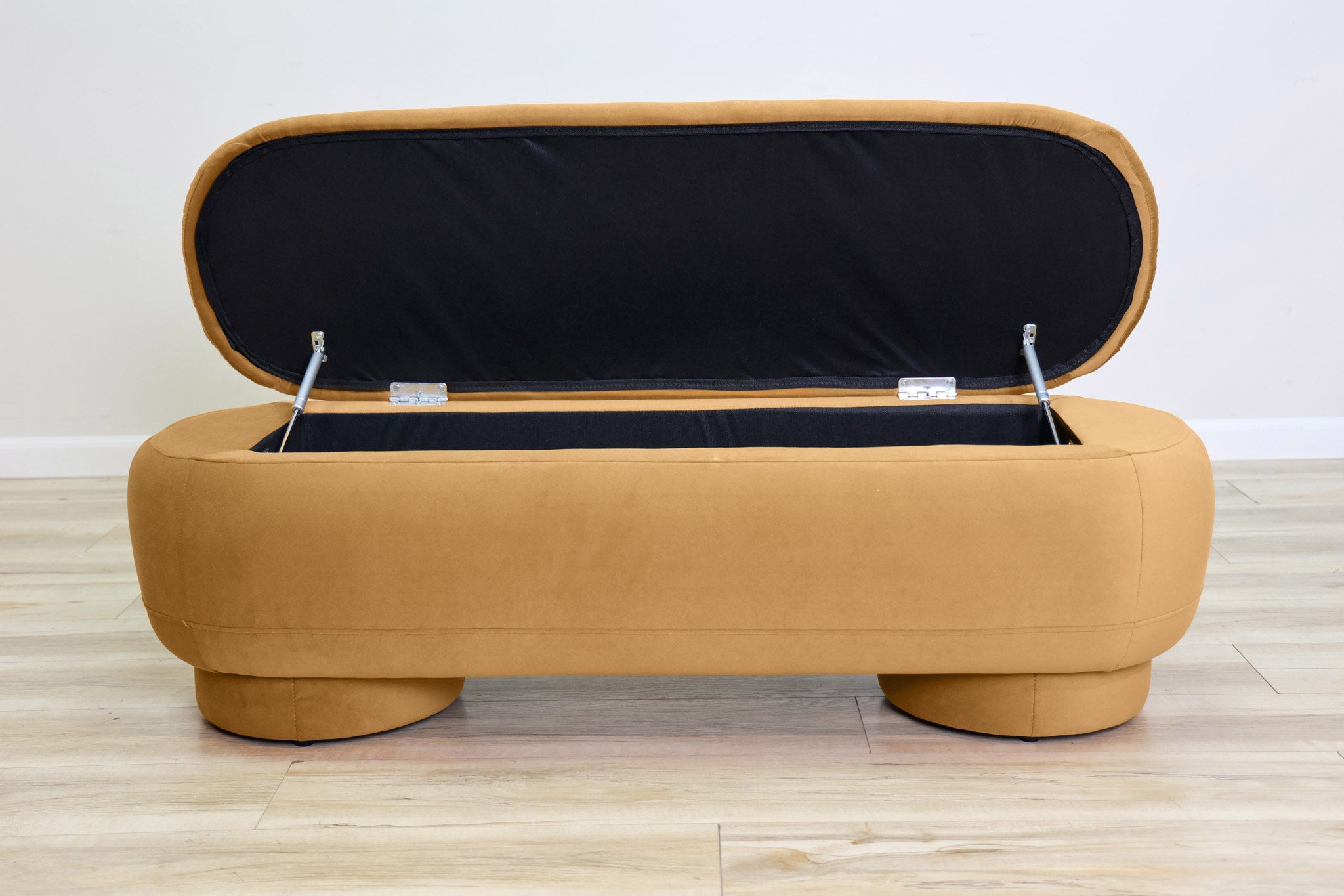 Dorian storage bench in golden velvet with a lift-top lid open to hidden storage and rounded drum feet, living room