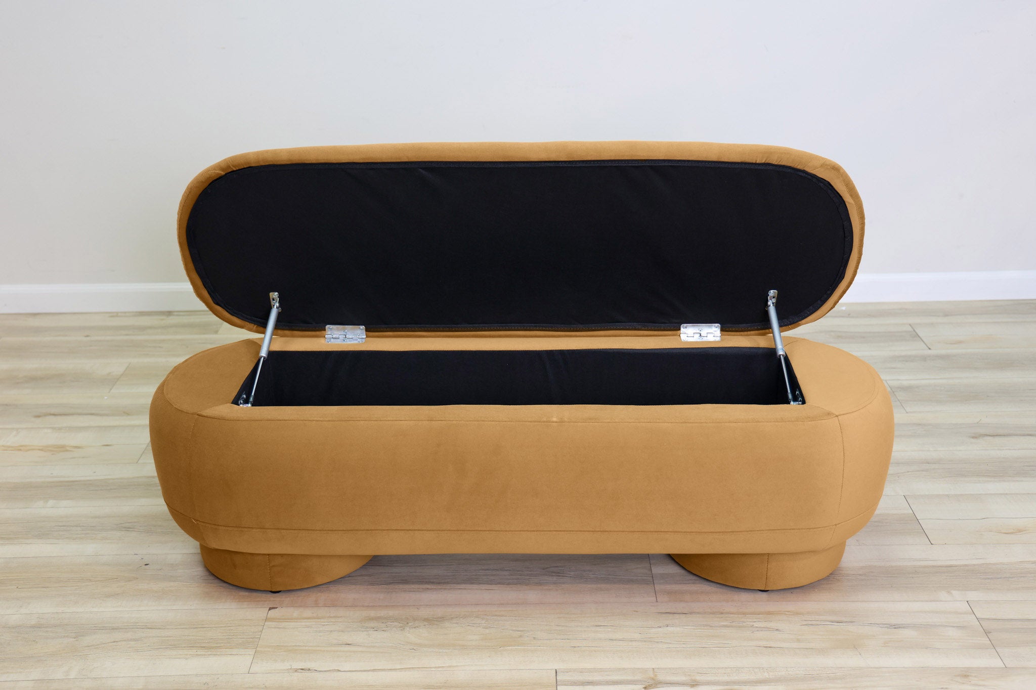 Dorian storage bench in golden velvet with a lift-top lid open to hidden storage and rounded drum feet, living room
