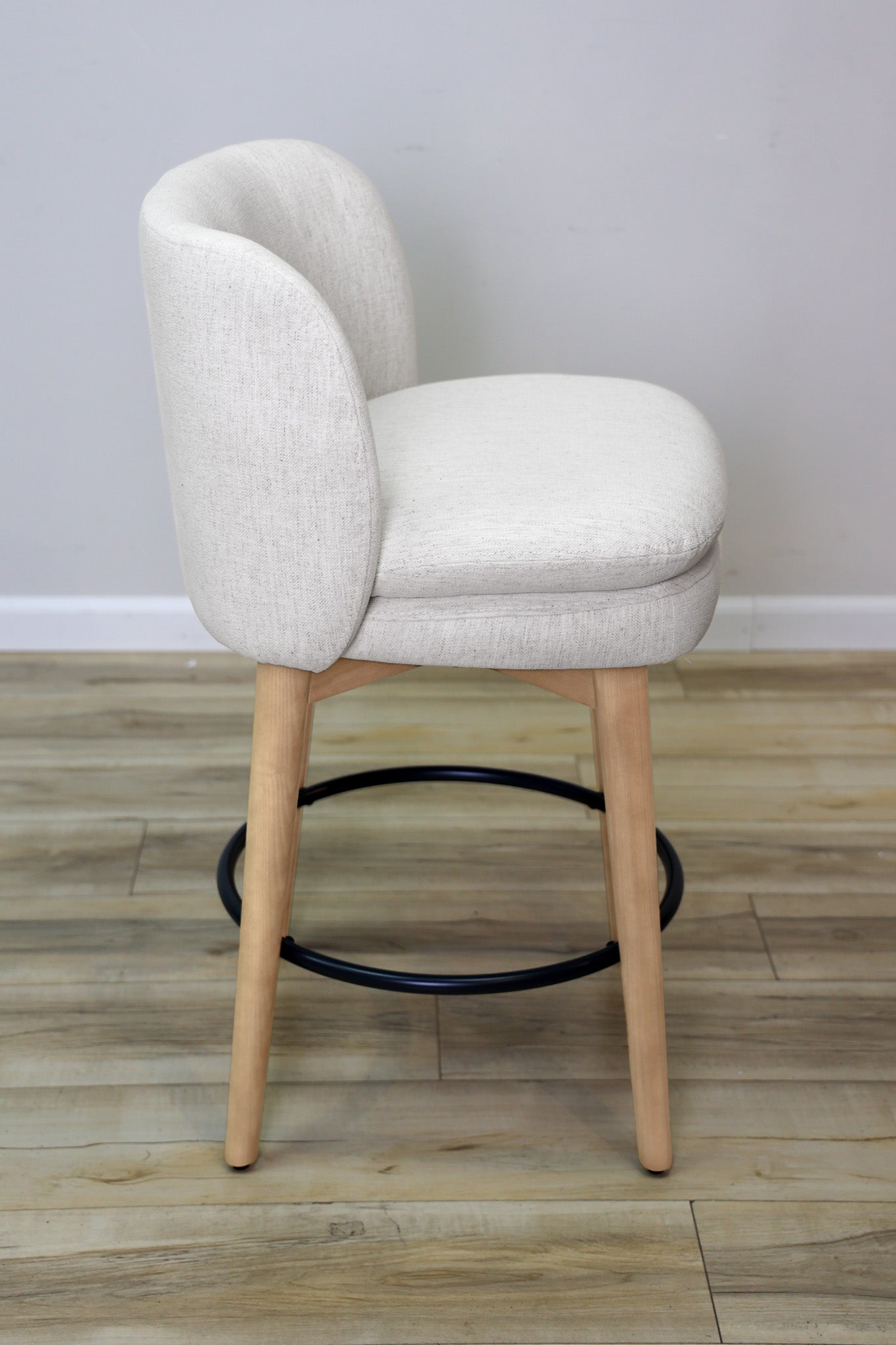 Tiffany swivel counter stool in ivory Crypton fabric with natural wood legs and a black ring footrest, kitchen counter