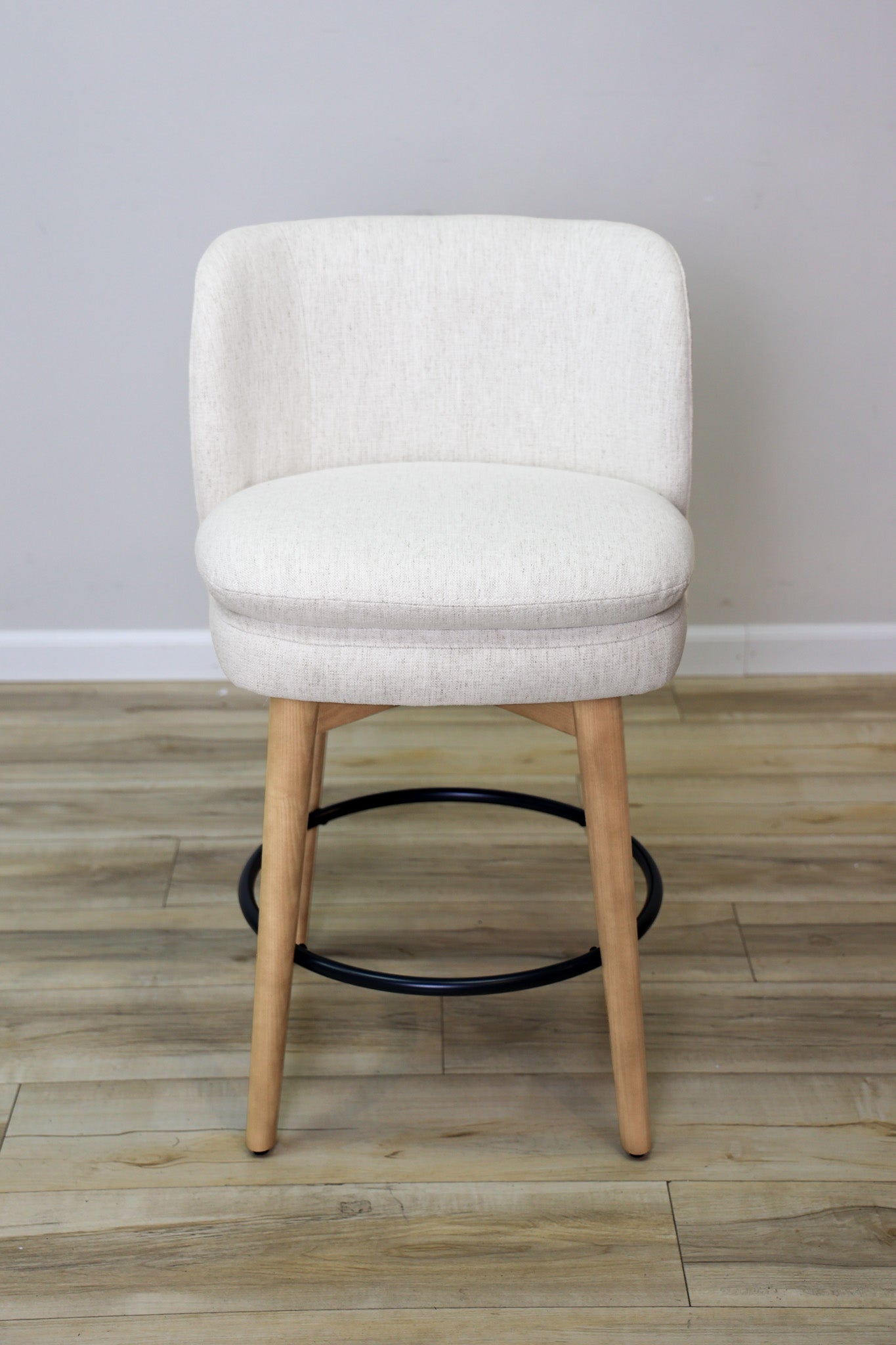 Tiffany swivel counter stool in ivory Crypton fabric with natural wood legs and a black ring footrest, kitchen counter