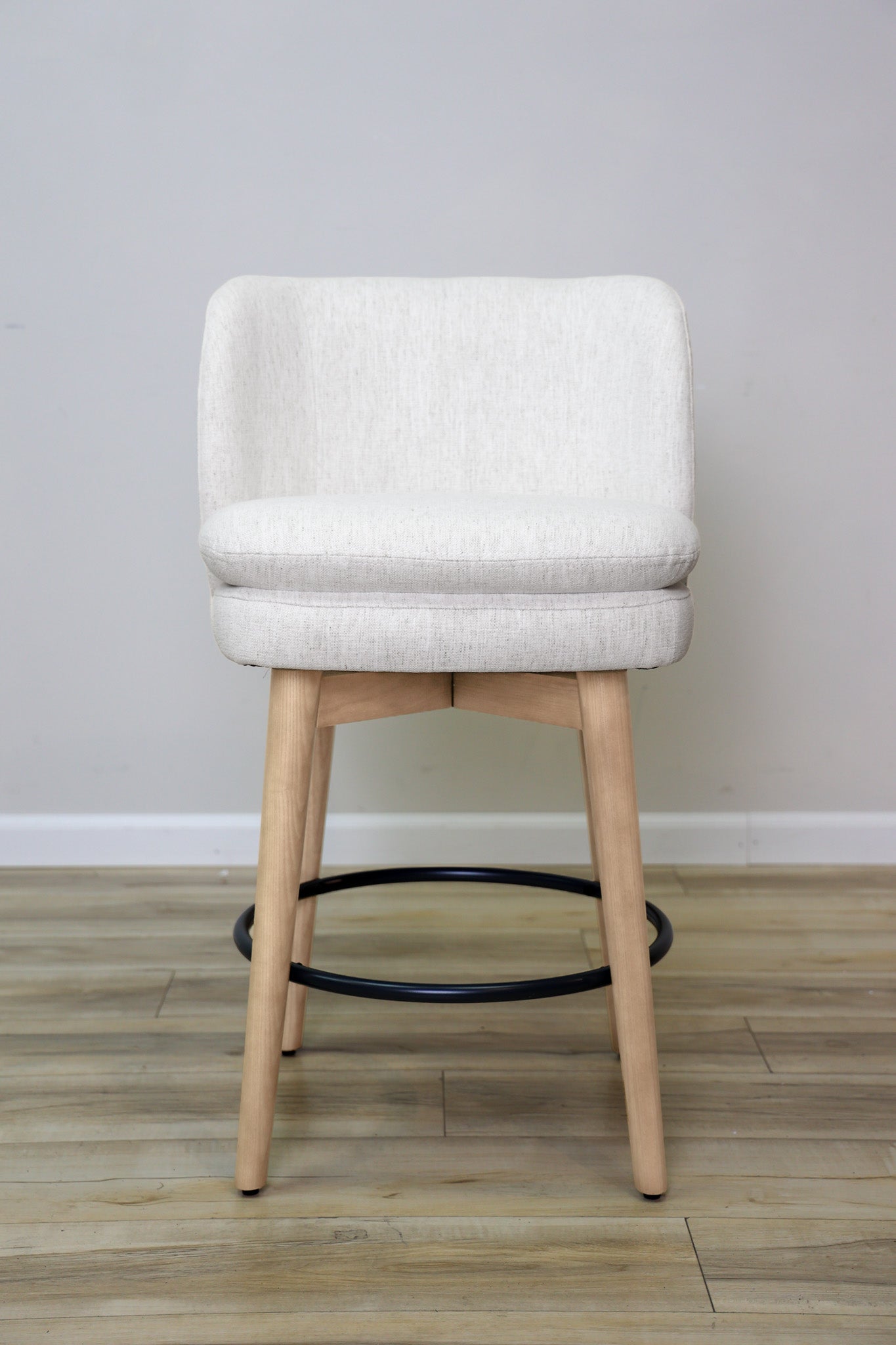 Tiffany swivel counter stool in ivory Crypton fabric with natural wood legs and a black ring footrest, kitchen counter