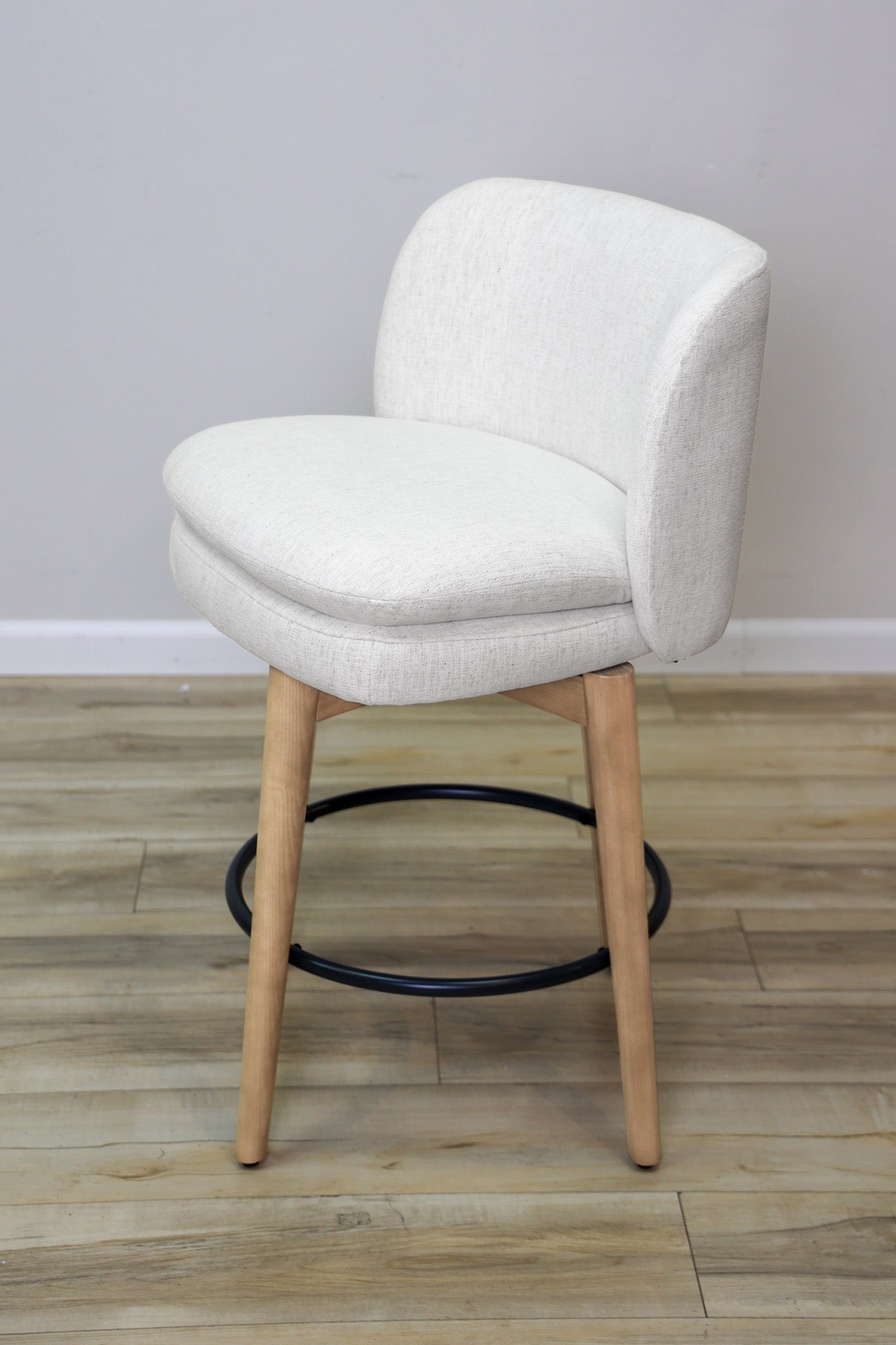 Tiffany swivel counter stool in ivory Crypton fabric with natural wood legs and a black ring footrest, kitchen counter