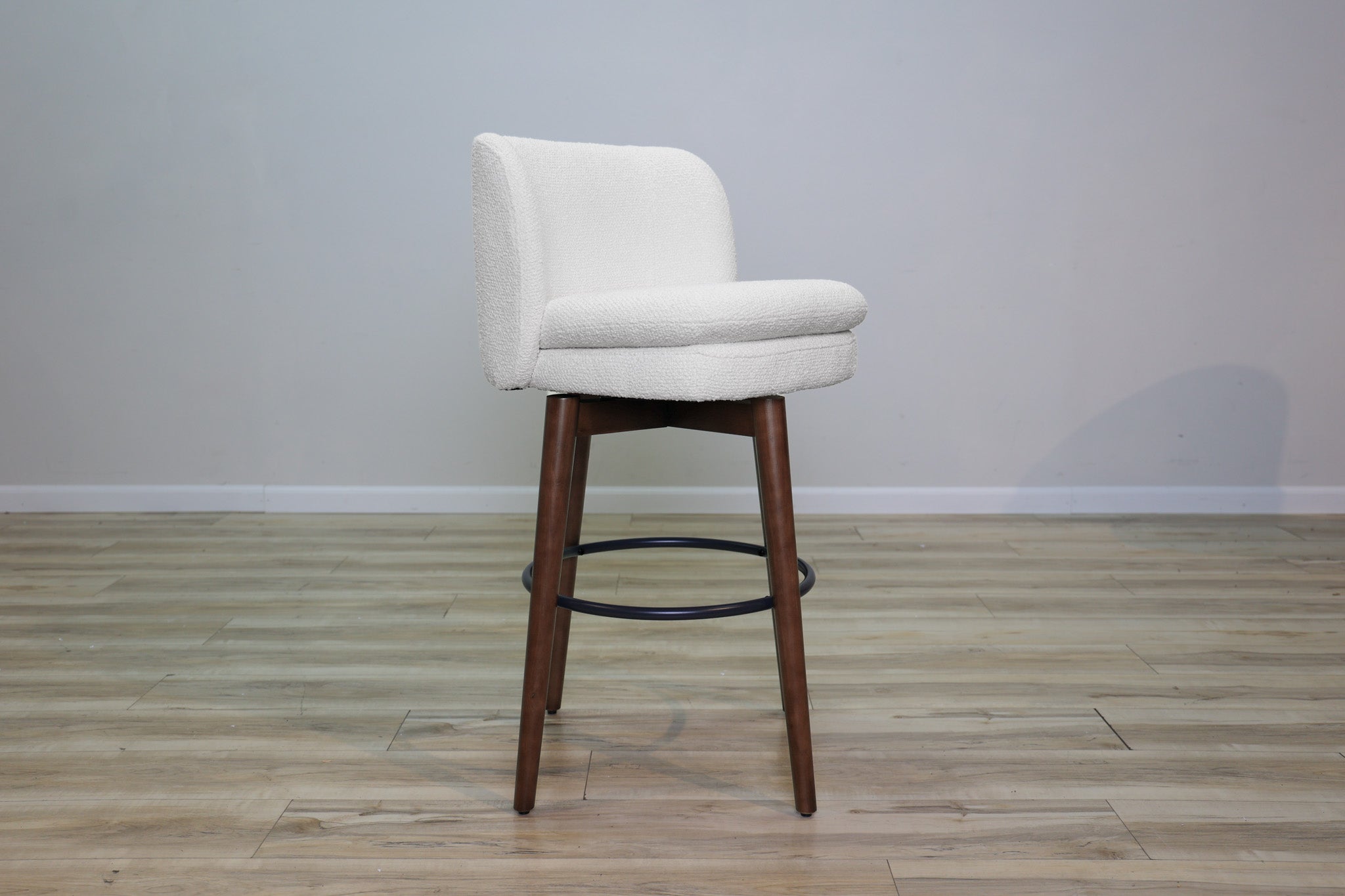 Avalon swivel barstool in cream bouclé performance fabric with walnut wood legs and a black ring footrest, kitchen bar