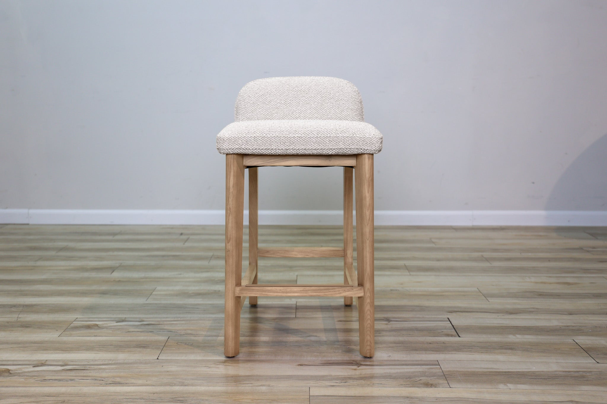 Asher counter stool in beige performance fabric with a low back and natural wood legs with stretchers, kitchen counter