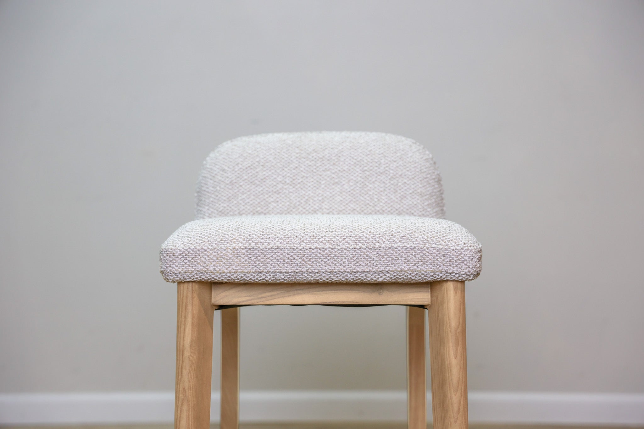 Asher counter stool in beige performance fabric with a low back and natural wood legs with stretchers, kitchen counter