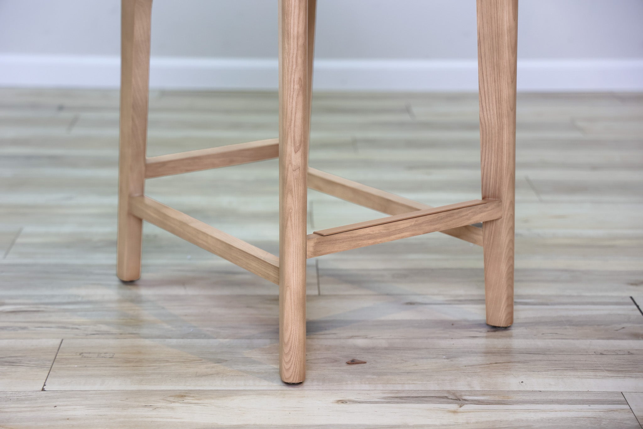 Asher counter stool in beige performance fabric with a low back and natural wood legs with stretchers, kitchen counter