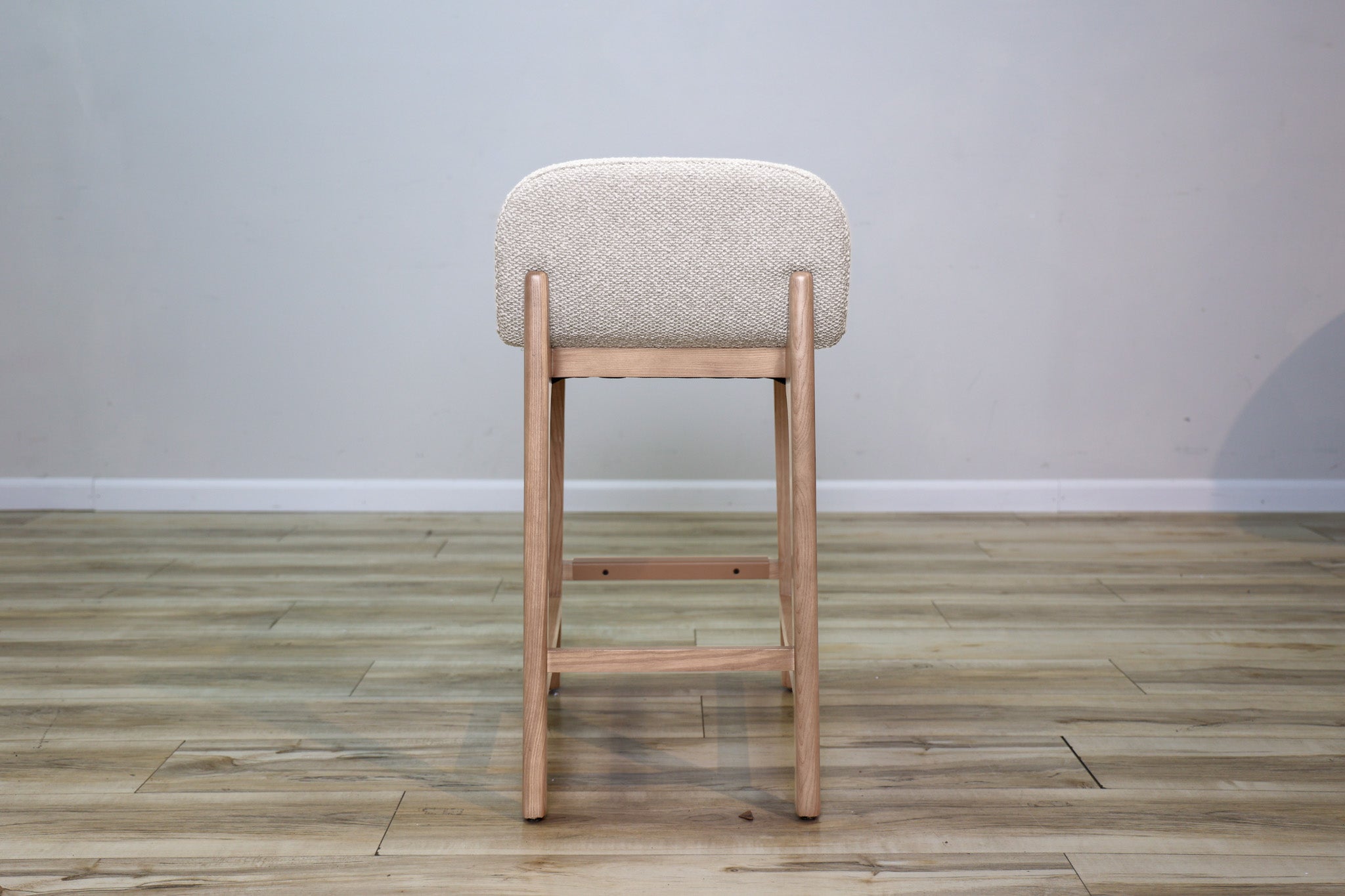 Asher counter stool in beige performance fabric with a low back and natural wood legs with stretchers, kitchen counter