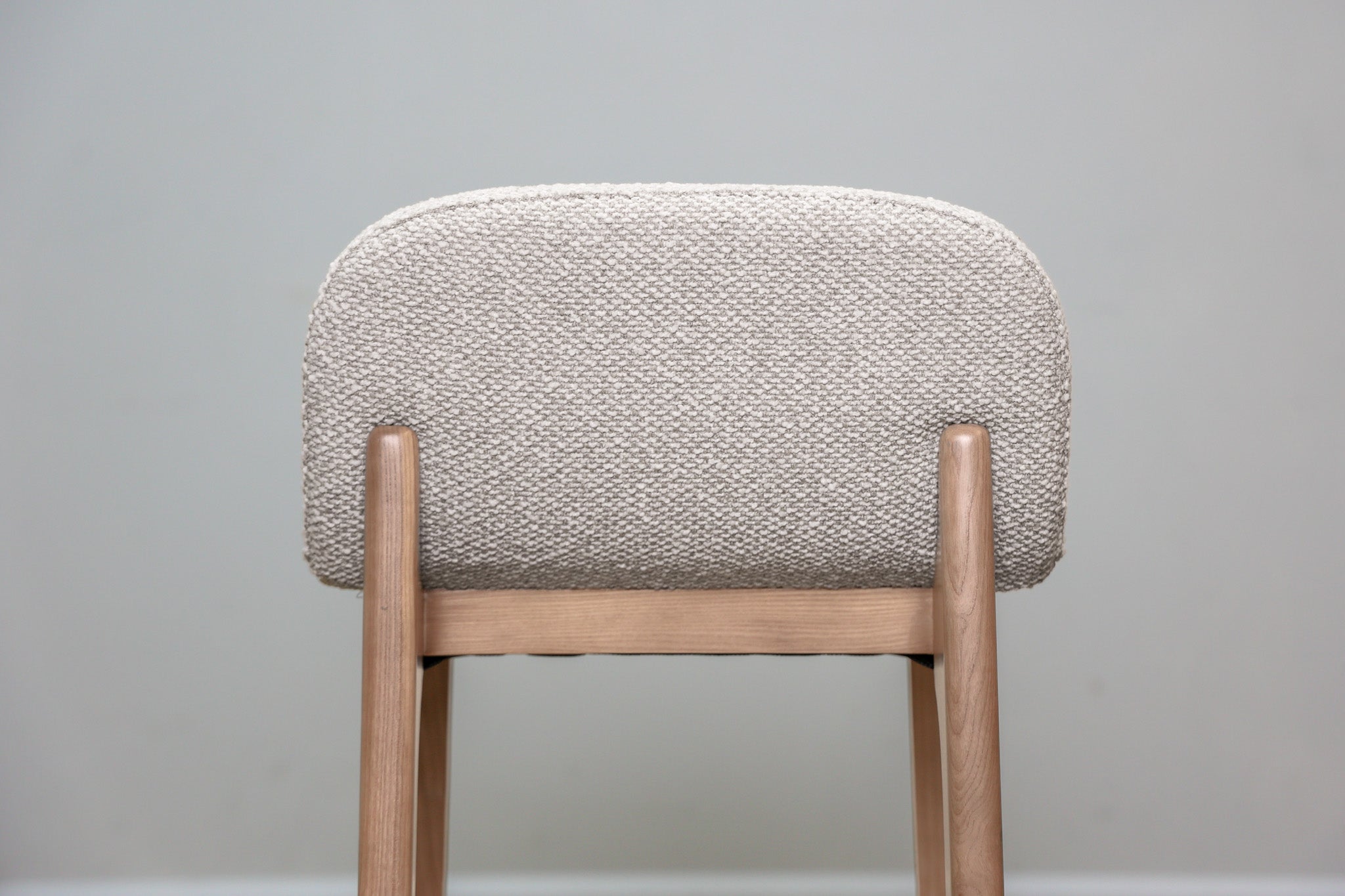 Asher counter stool in beige performance fabric with a low back and natural wood legs with stretchers, kitchen counter