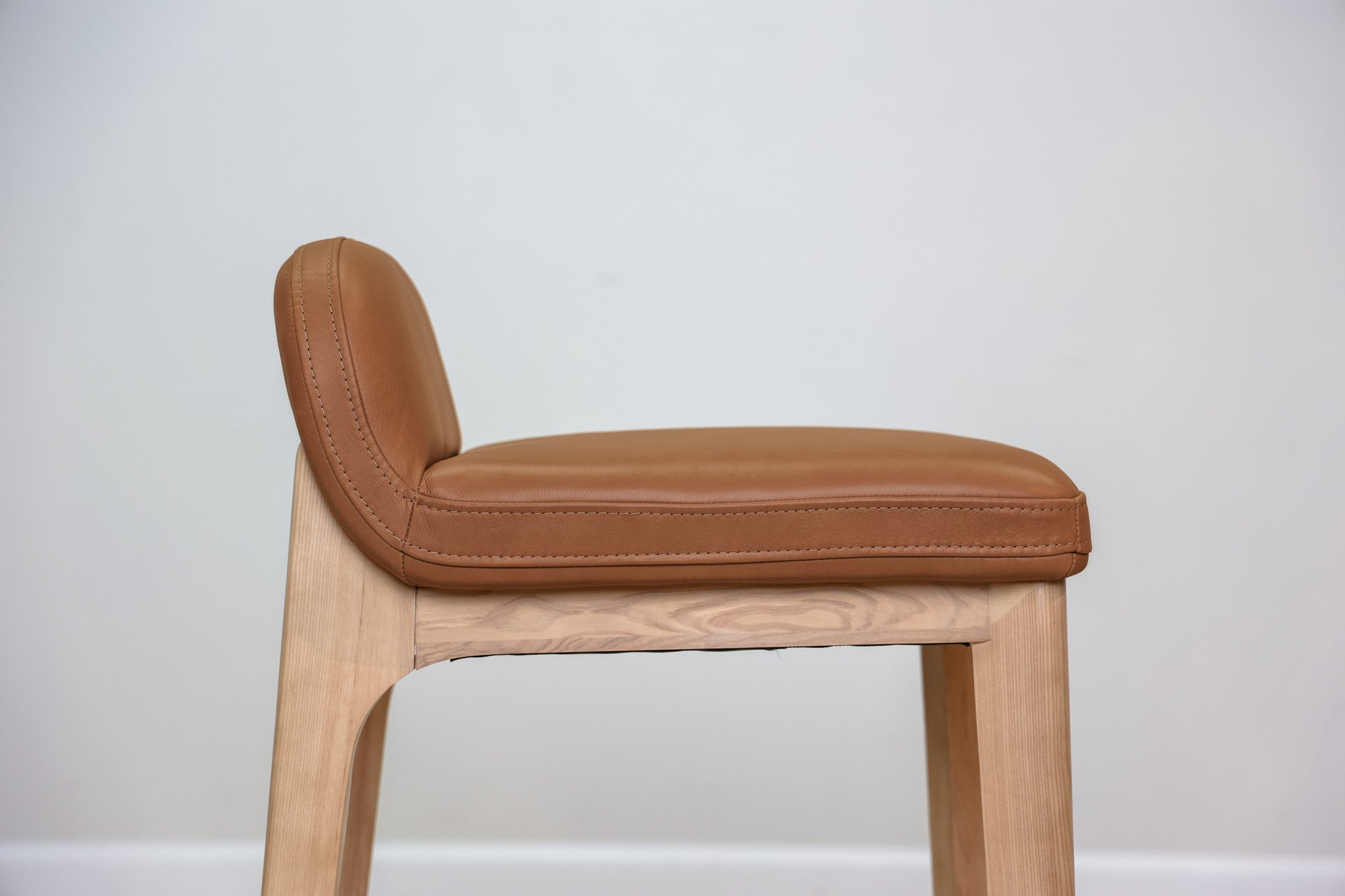 Sable counter stool in cognac leather with a low back and natural wood legs with stretchers, kitchen counter